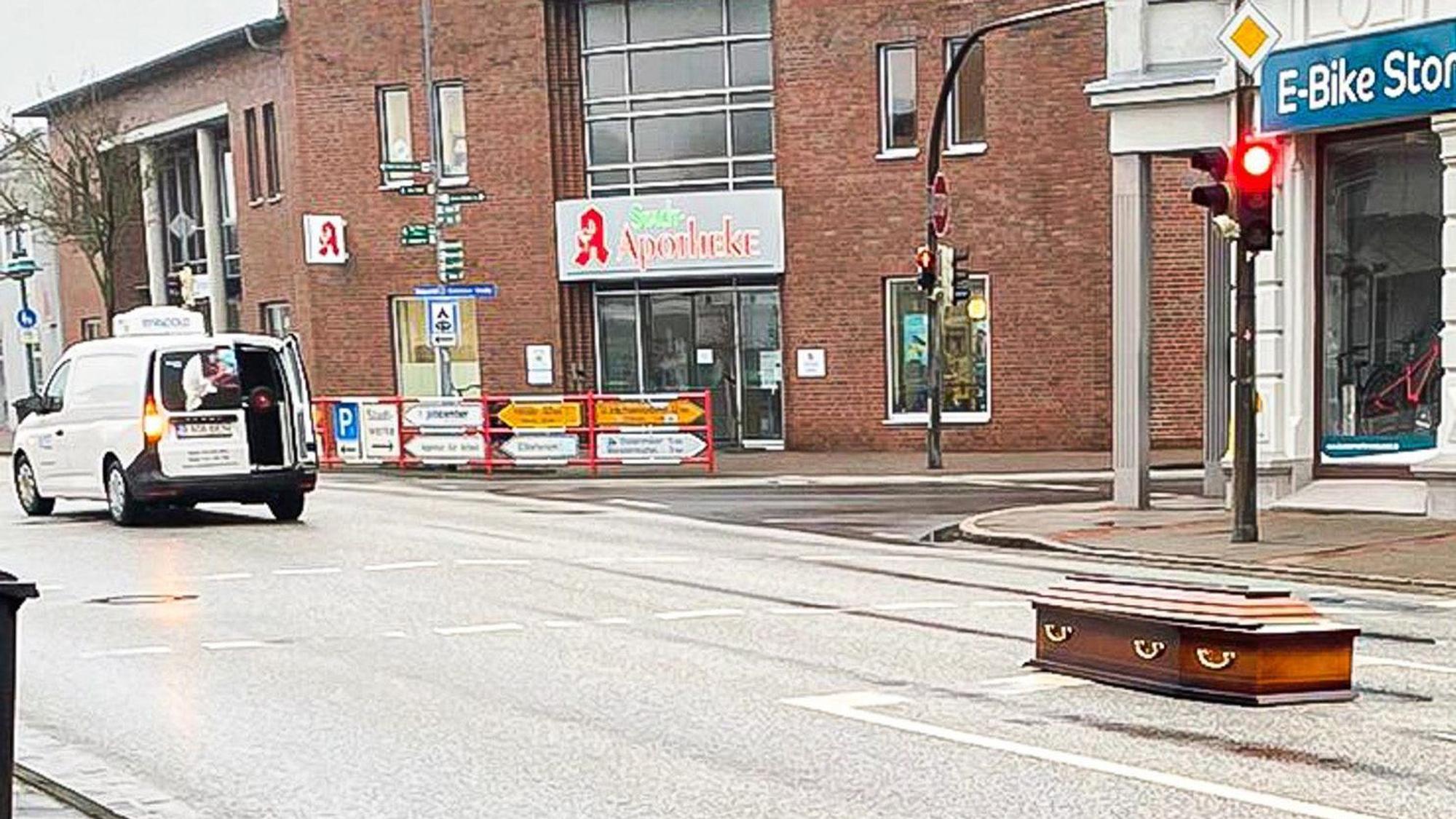 Ein Sarg liegt auf einer Straße. Für Aufsehen hat in Brunsbüttel ein aus einem Transporter gefallener Sarg gesorgt. Nach seinen Kenntnissen sei der Holzsarg am Freitag von der Ladefläche des Fahrzeugs auf die Straße gerutscht, sagte ein Polizeisprecher.