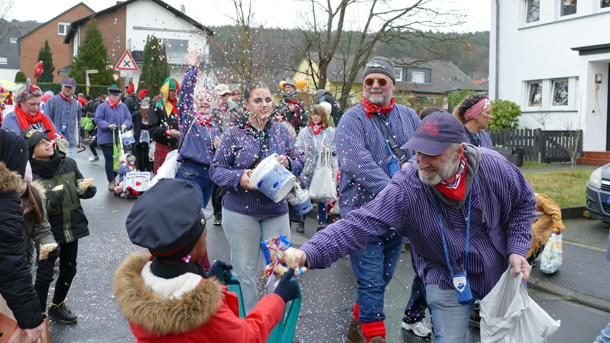Ein Karnevalist verteilt Kamelle an eine Frau.