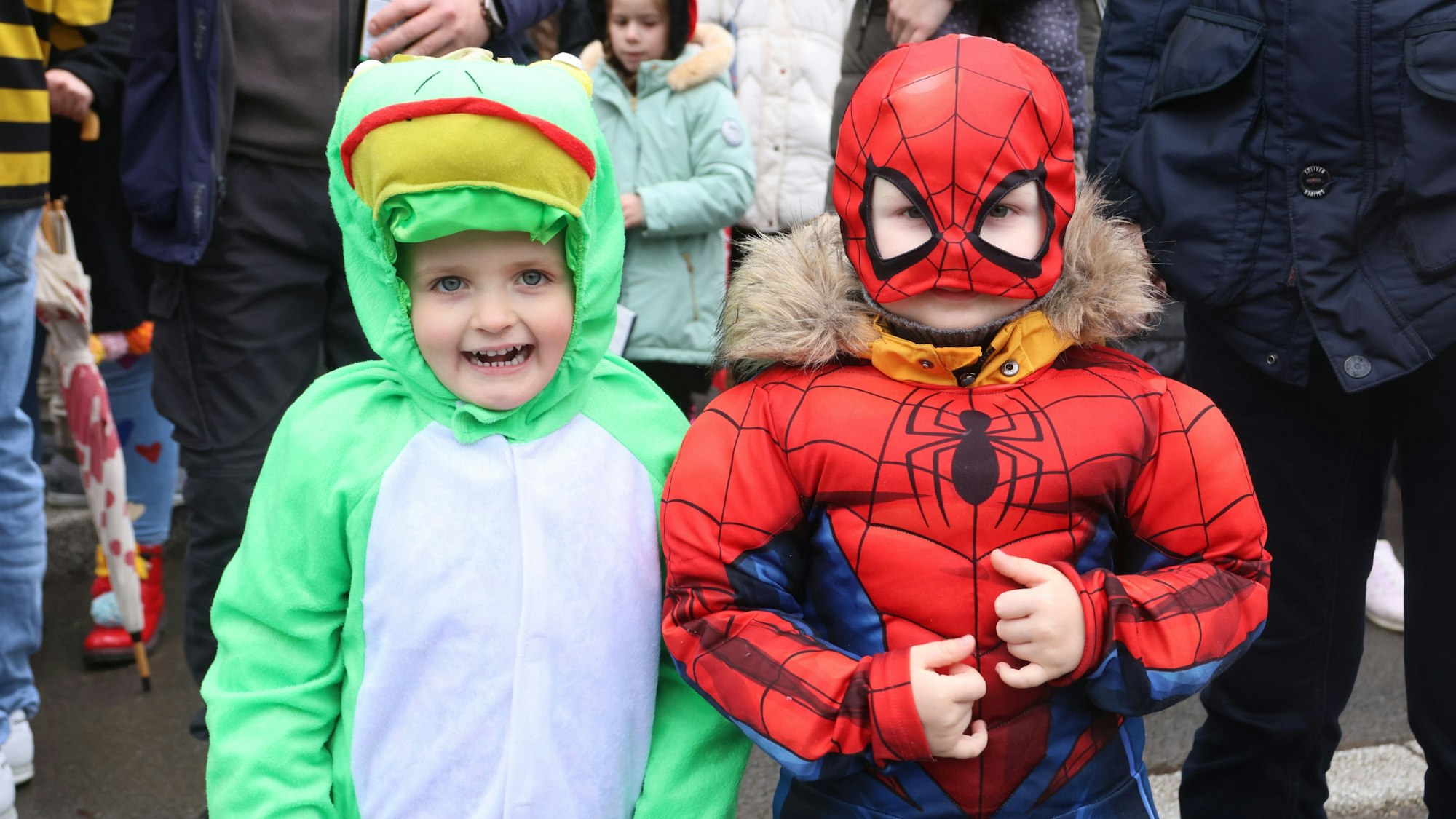 Zwei als Frosch und Spiderman verkleidete Kinder stehen am Straßenrand.