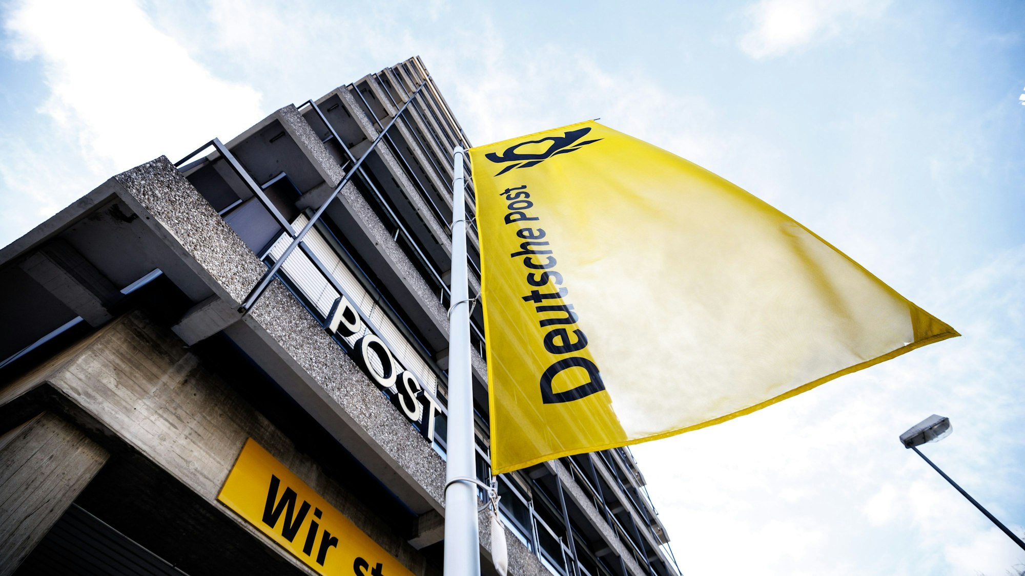 Eine Fahne mit der Aufschrift „Deutsche Post“ weht während einer Kundgebung anlässlich bundesweiter Warnstreiks bei der Deutschen Post vor einem Briefzentrum.