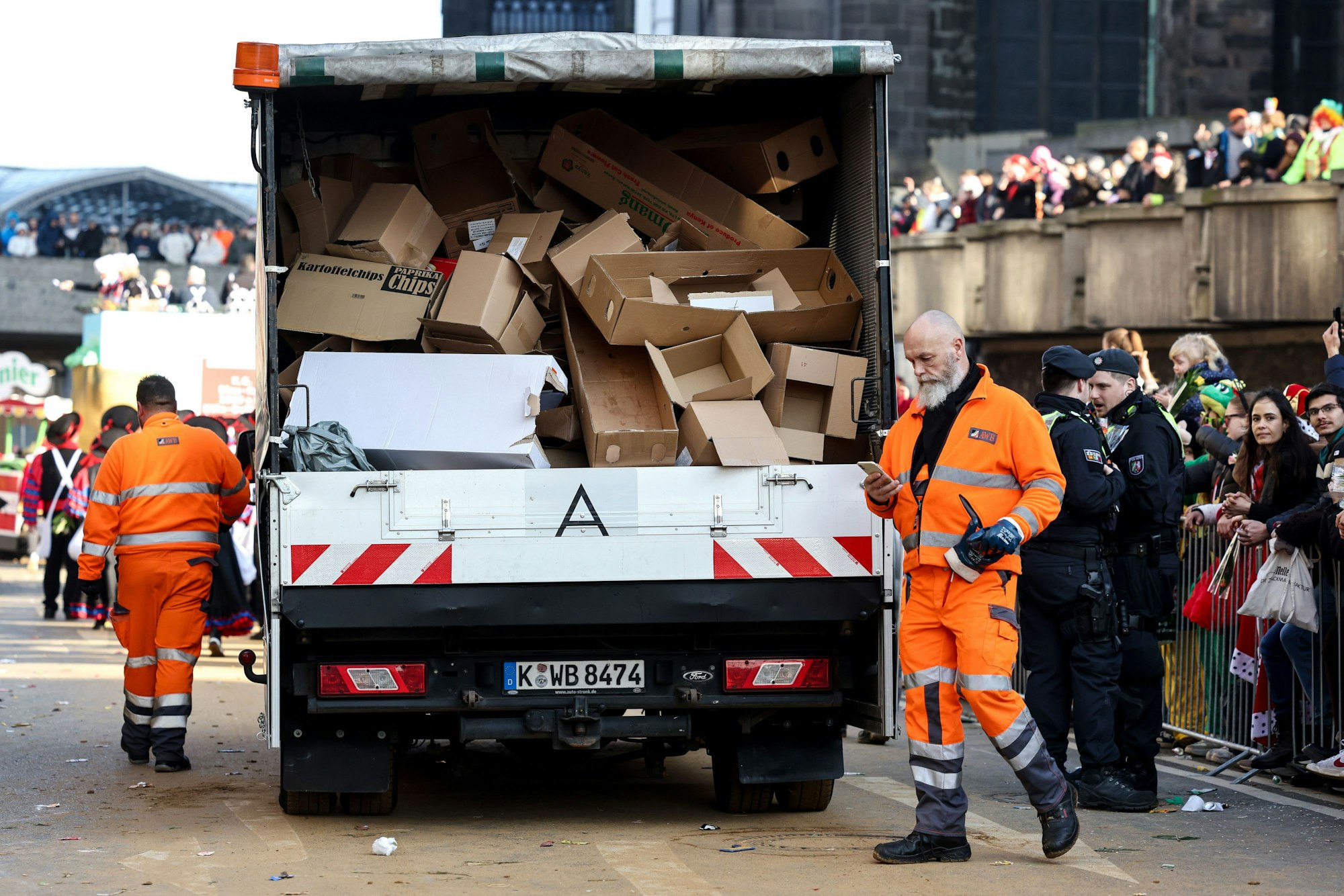 Mitarbeiter der Stadtreinigung sammeln leere Pappkartons am Kölner Dom ein.