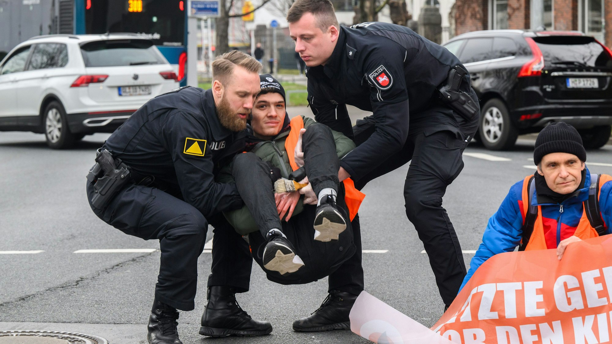 Hannover: Polizisten tragen zuvor am Asphalt festgeklebte Aktivisten der Gruppierung Letzte Generation von der Straße.