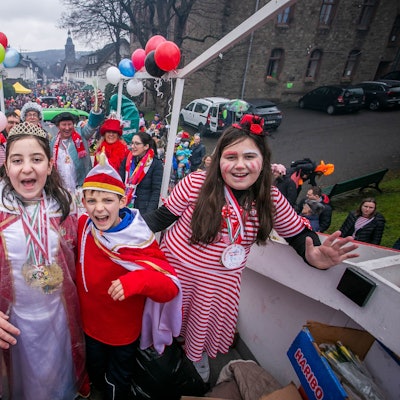 Vier verkleidete Kinder stehen auf einem Karnevalszug.