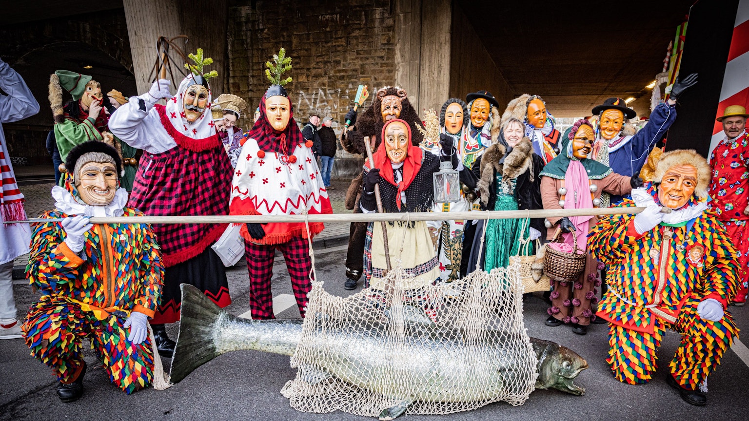 Mitglieder der Vereinigung Schwäbisch-Alemannischer Narrenzünfte stellen sich zum Gruppenfoto auf. Hingucker ist ein riesiger Fisch, den zwei Vertreter an einem Stamm durch die Straßen tragen.