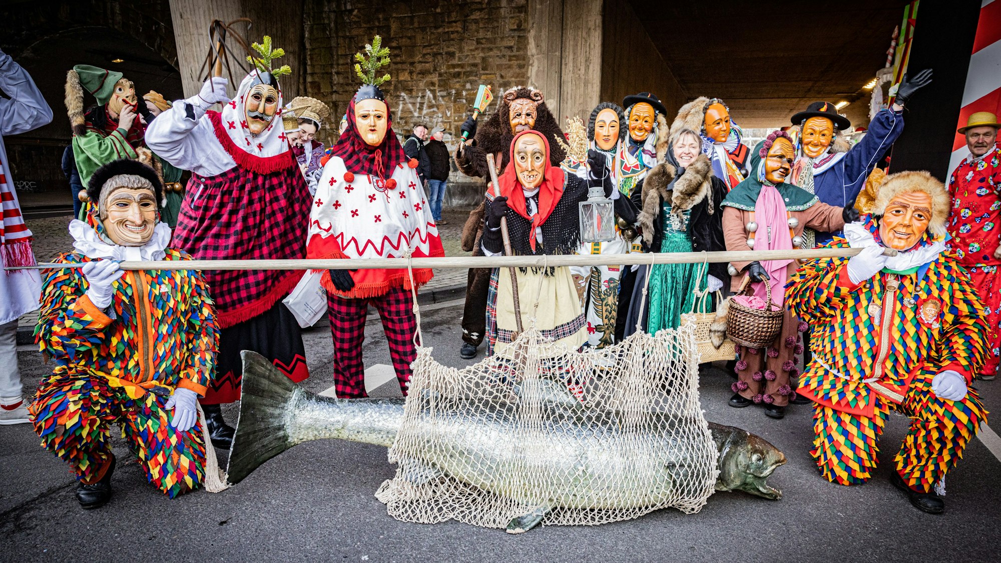 Mitglieder der Vereinigung Schwäbisch-Alemannischer Narrenzünfte stellen sich zum Gruppenfoto auf. Hingucker ist ein riesiger Fisch, den zwei Vertreter an einem Stamm durch die Straßen tragen.
