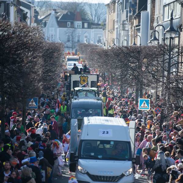 Wagen des Rosenmontagszugs in Euskirchen fahren durch die Wilhelmstraße. Links und rechts stehen zahlreiche Besucher.