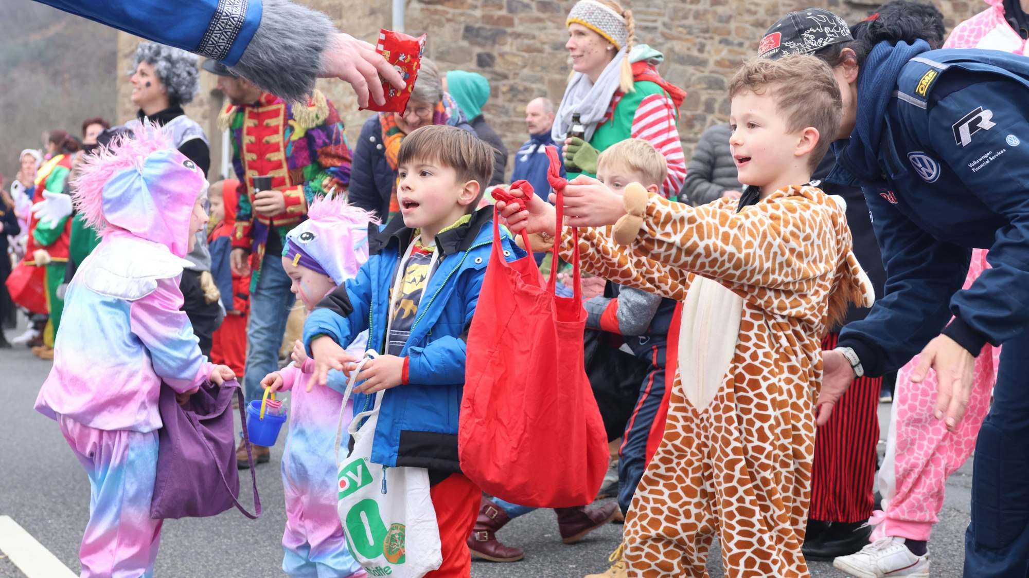 Zuschauer erwarten am Straßenrand Kamelle bei einem Karnevalsumzug.