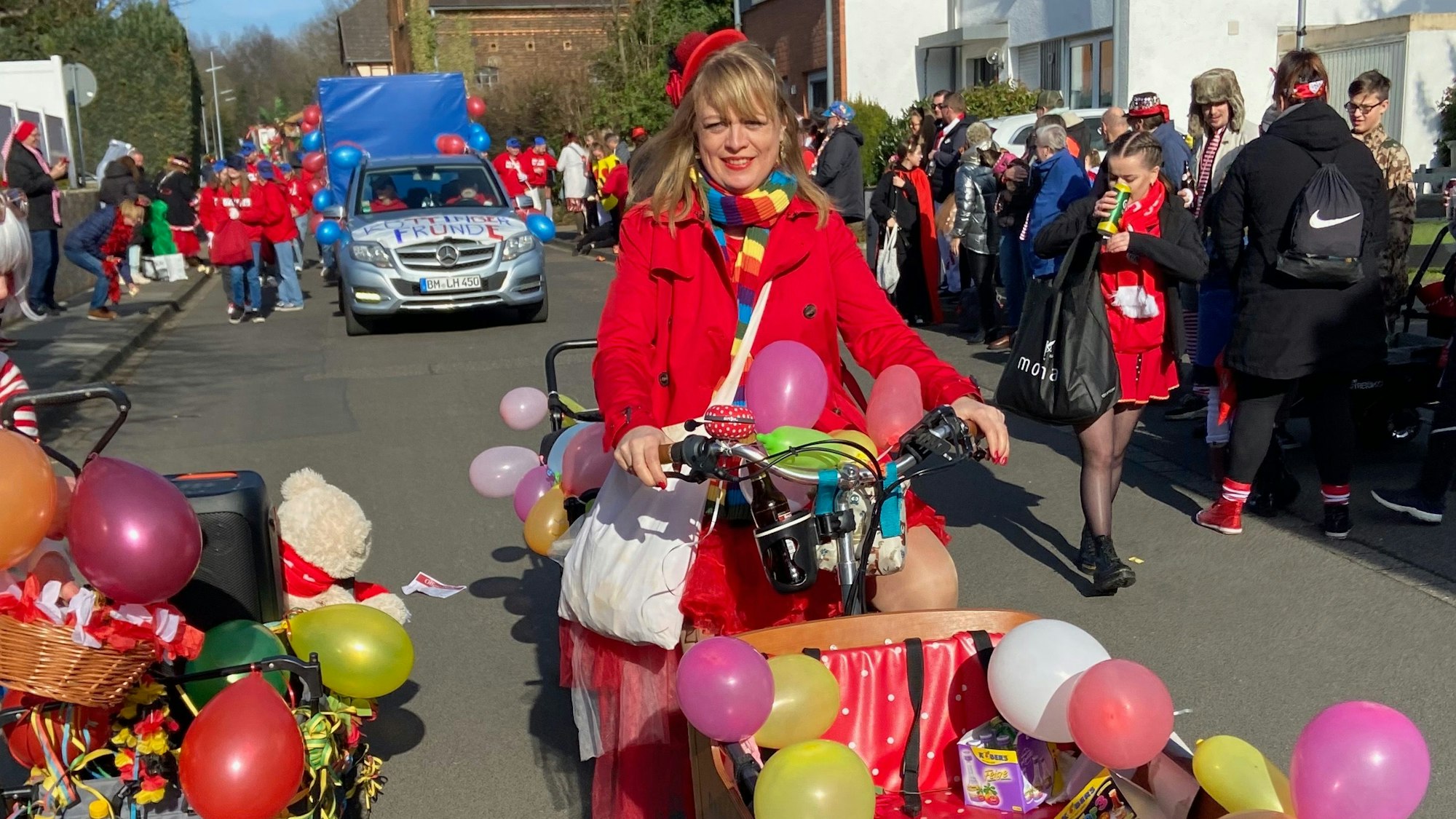 Eine bunt verkleidete Karnevalistin fährt mit ihrem Lastenrad im Zug mit.