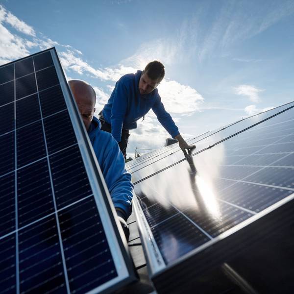 Zwei Handwerker bei der Montage von Photovoltaikmodulen auf einem Hausdach.