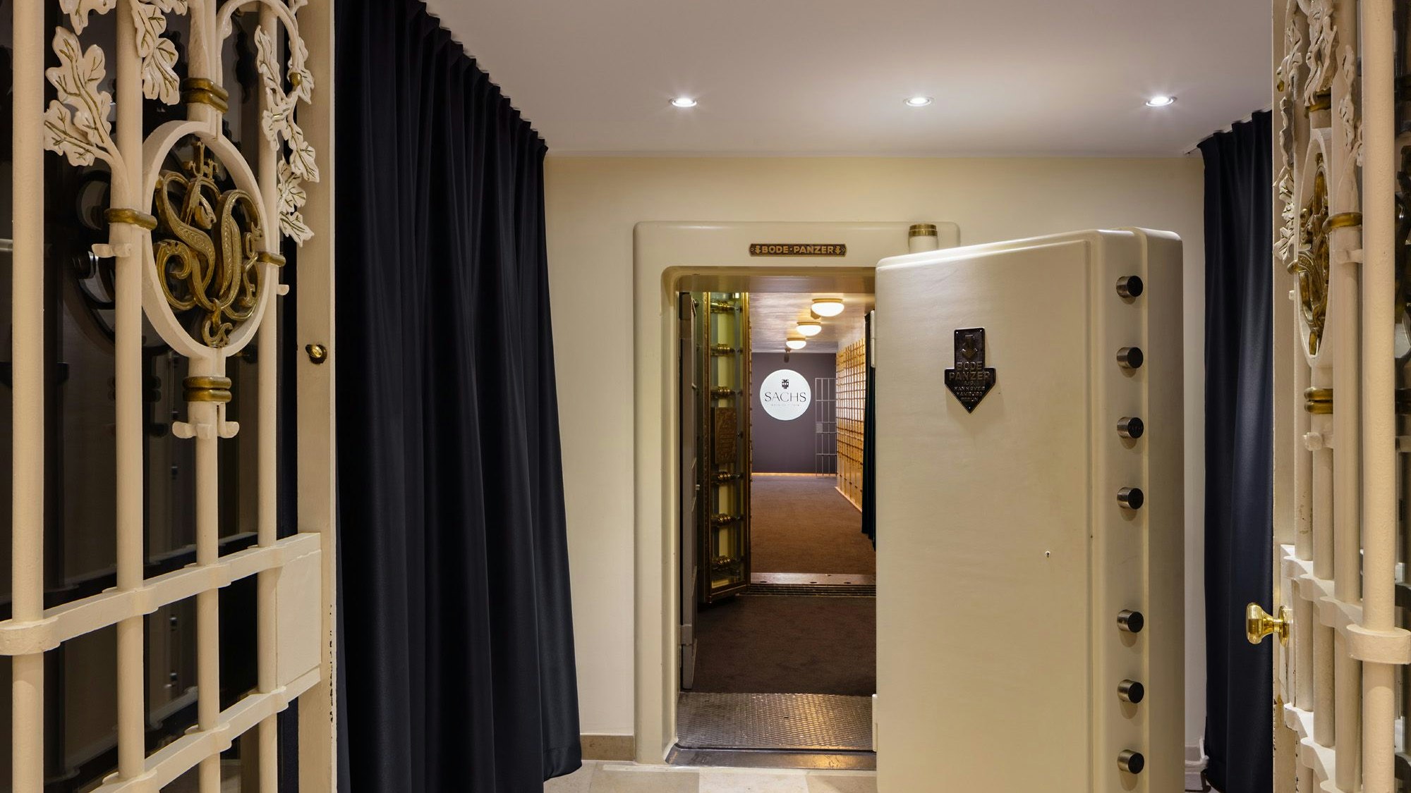 Hinter Gittertore mit vergoldeten Emblemen der früheren Sal. Oppenheim-Privatbank steht eine schwer aussehende Stahltür mit großen Schließgittern.