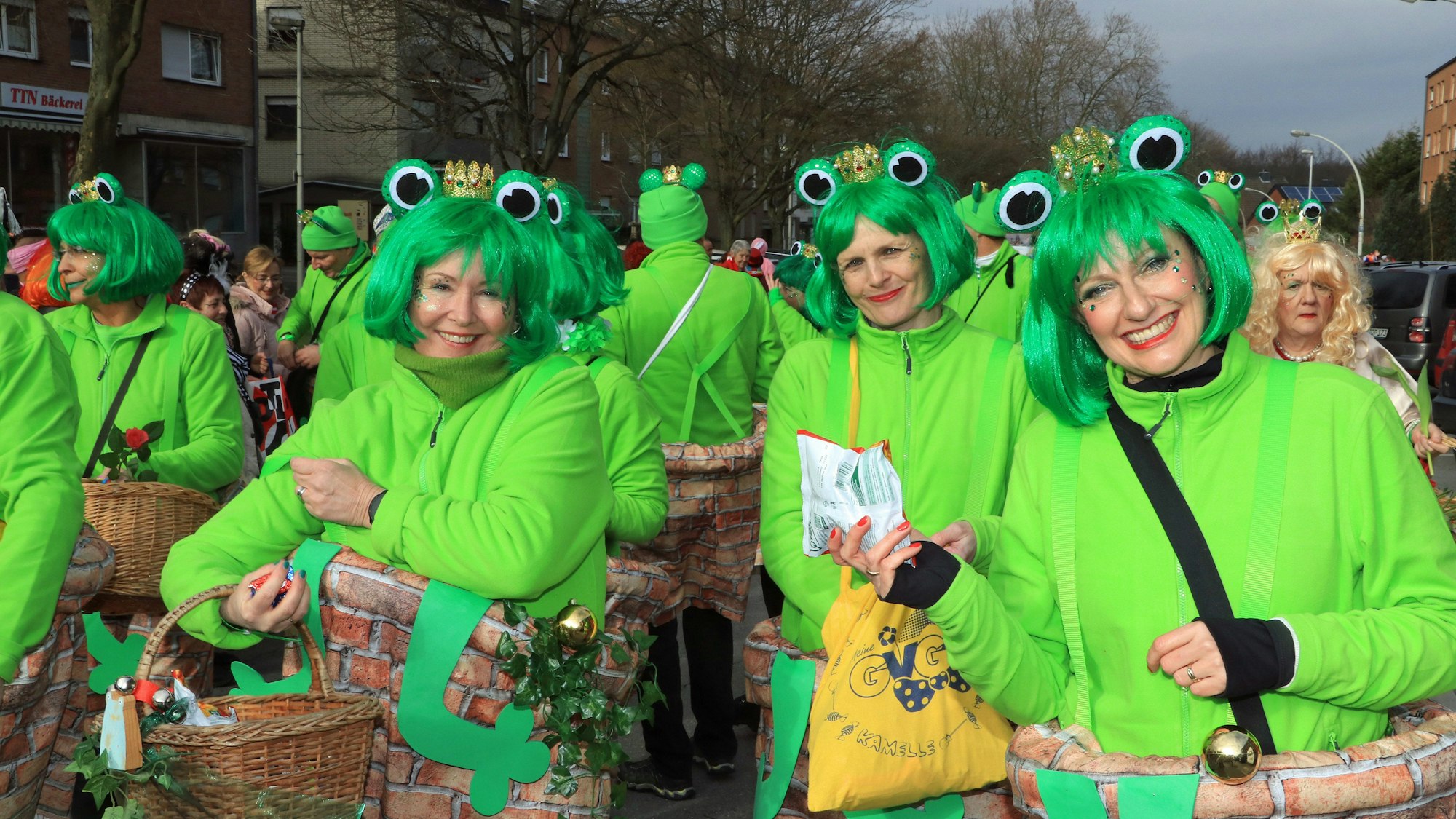 Frauen haben sich als knallgrüne Frösche verkleidet und lächeln in die Kamera.