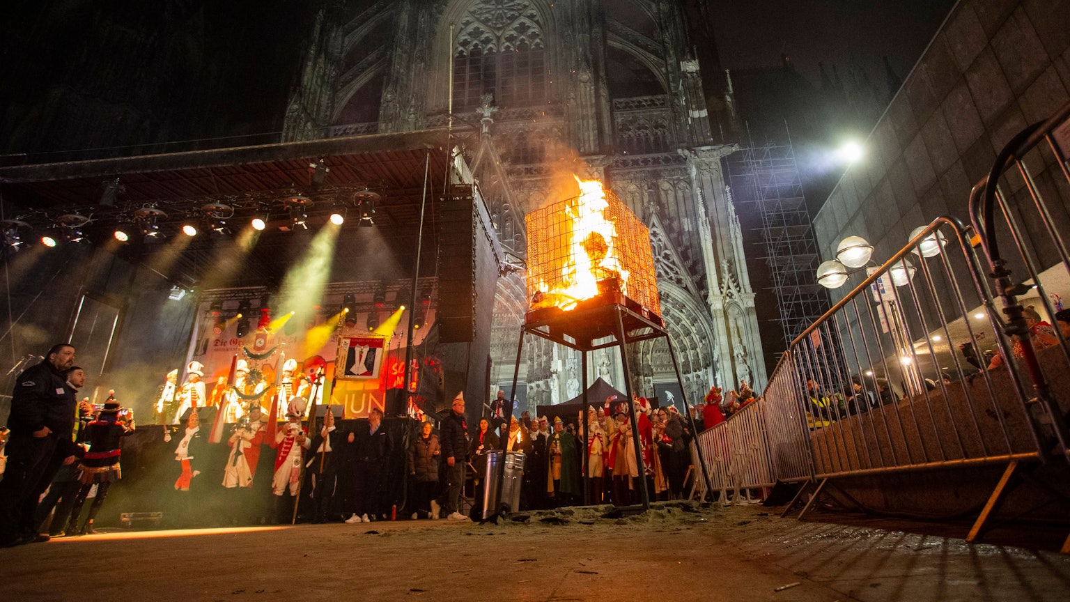 Vor dem angestrahlten Dom brennt der Nubbel in einem Käfig.