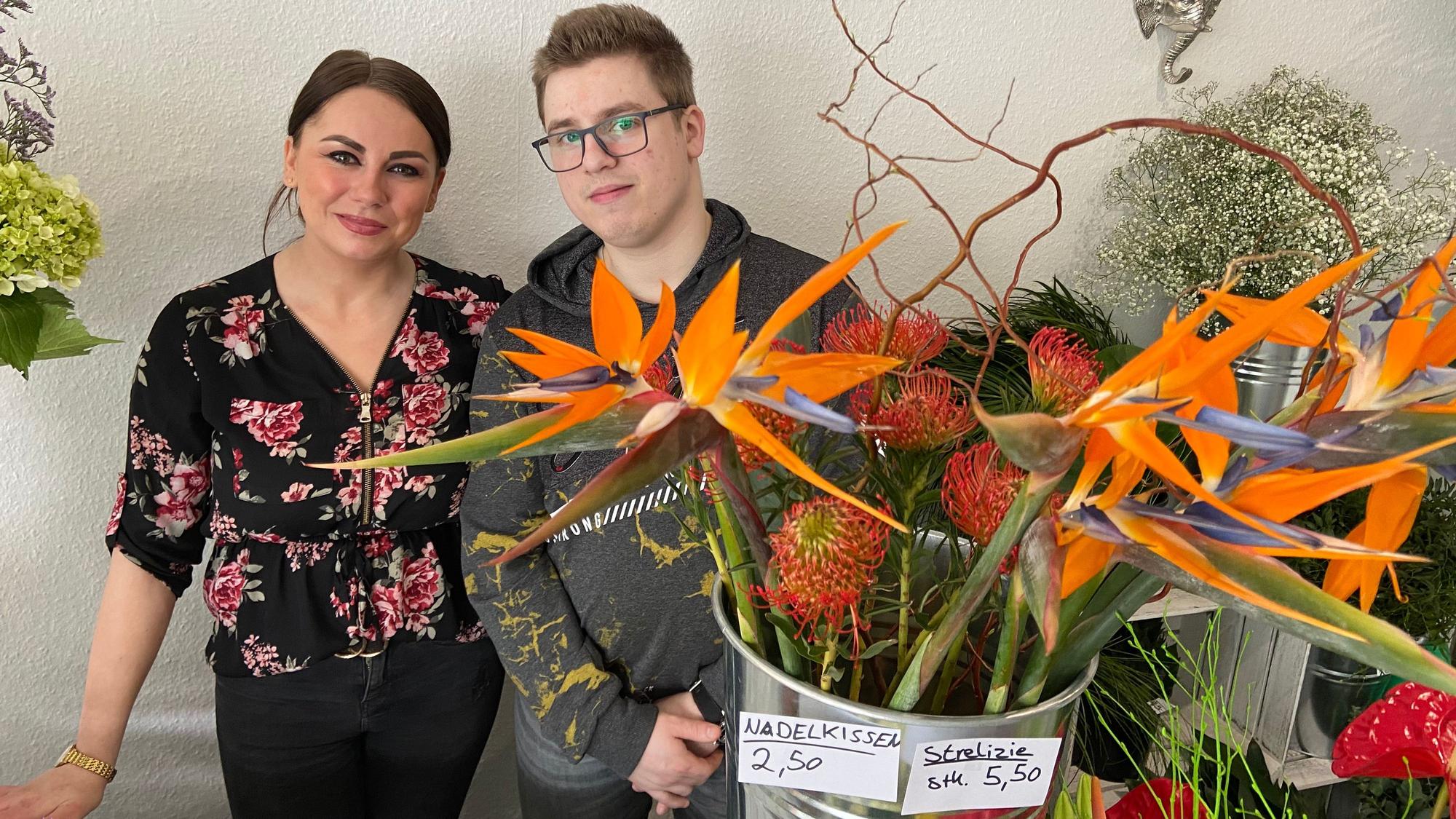 Auf dem Foto sind die Existenzgründer Joline Altstadt und Rafael Gassen zu sehen. Sie stehen inmitten bunter Blumen.