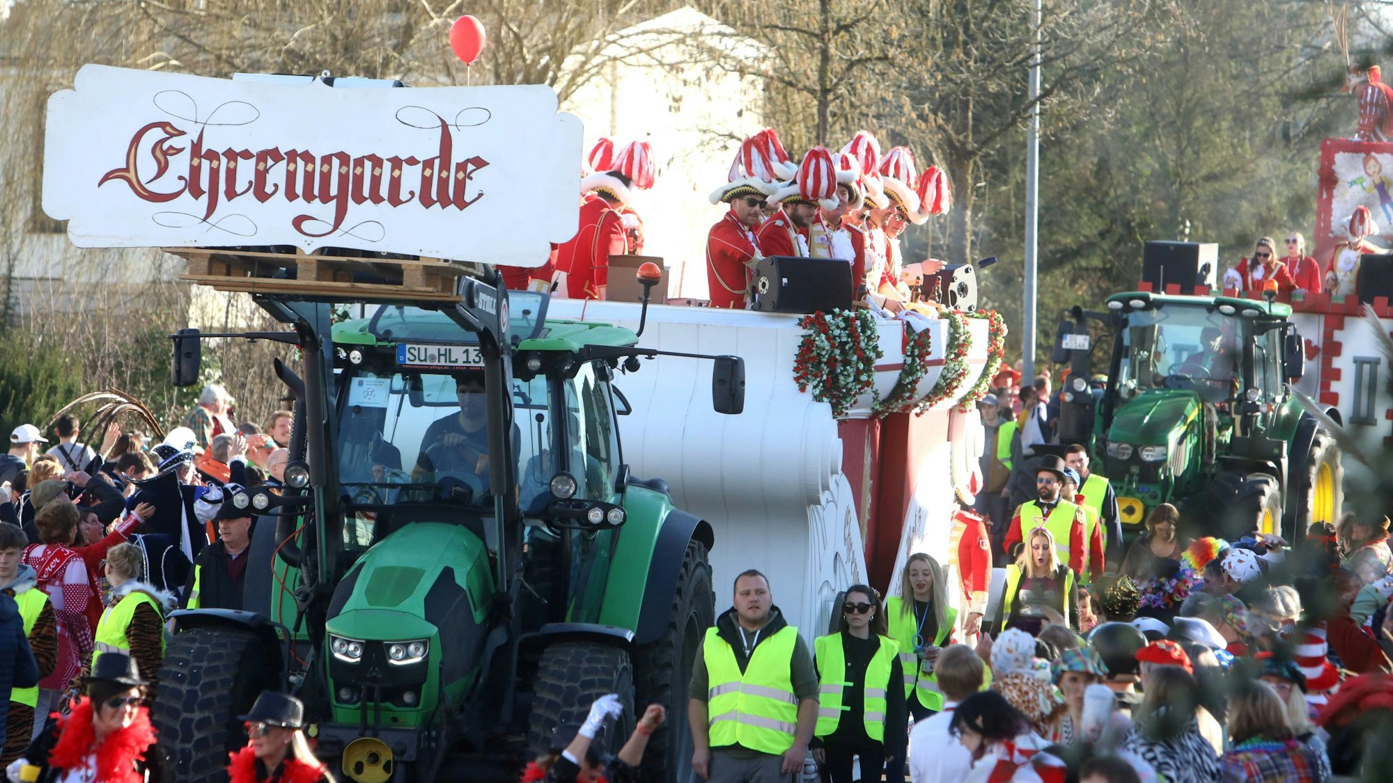 Ein Traktor mit dem großen Schriftzug „Ehrengarde“ zieht einen Festwagen durch die Straßen.