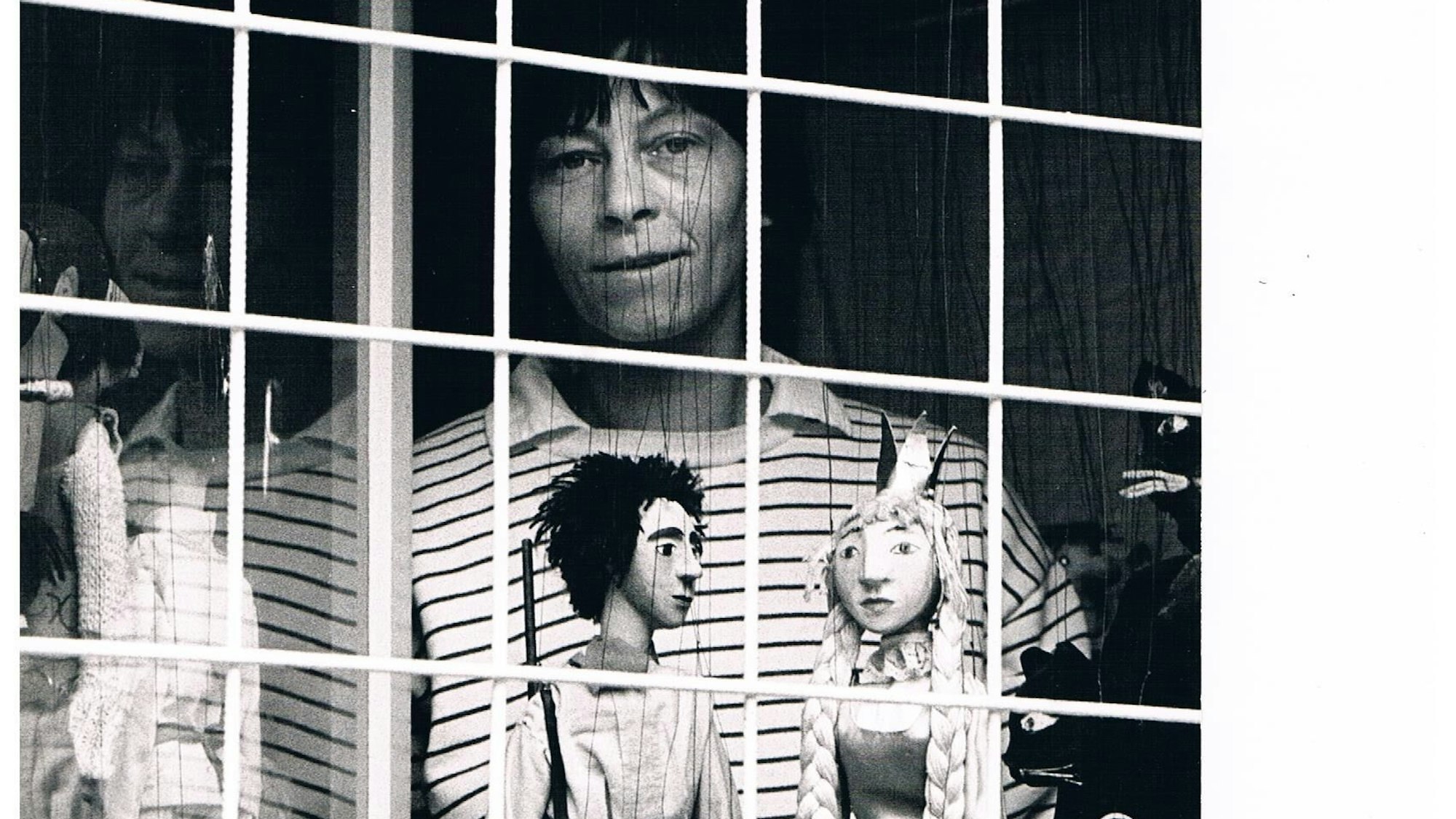 Ruth Schröder steht an einem Fenster mit ihren Puppen.