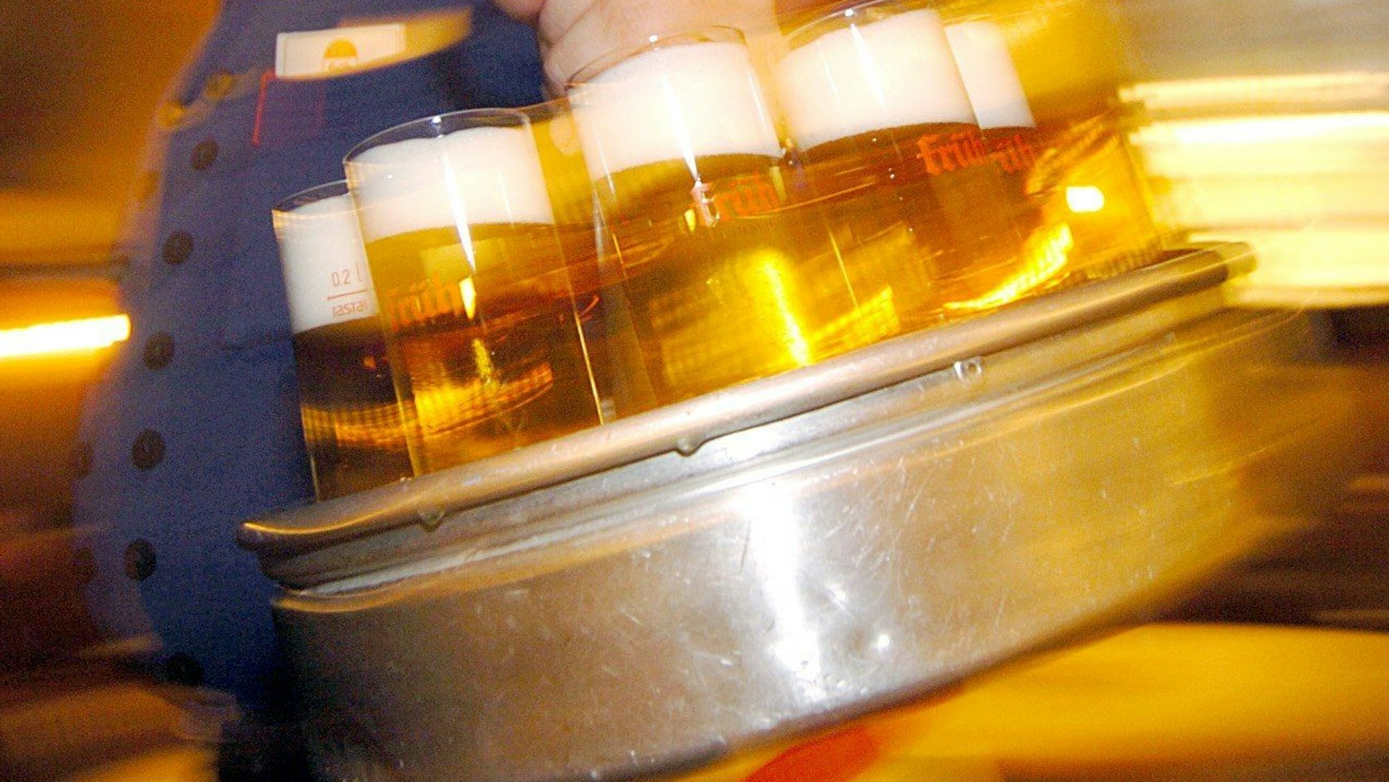 Ein Wirt in einem Kölsch-Brauhaus in der Kölner Innenstadt serviert Kölsch.