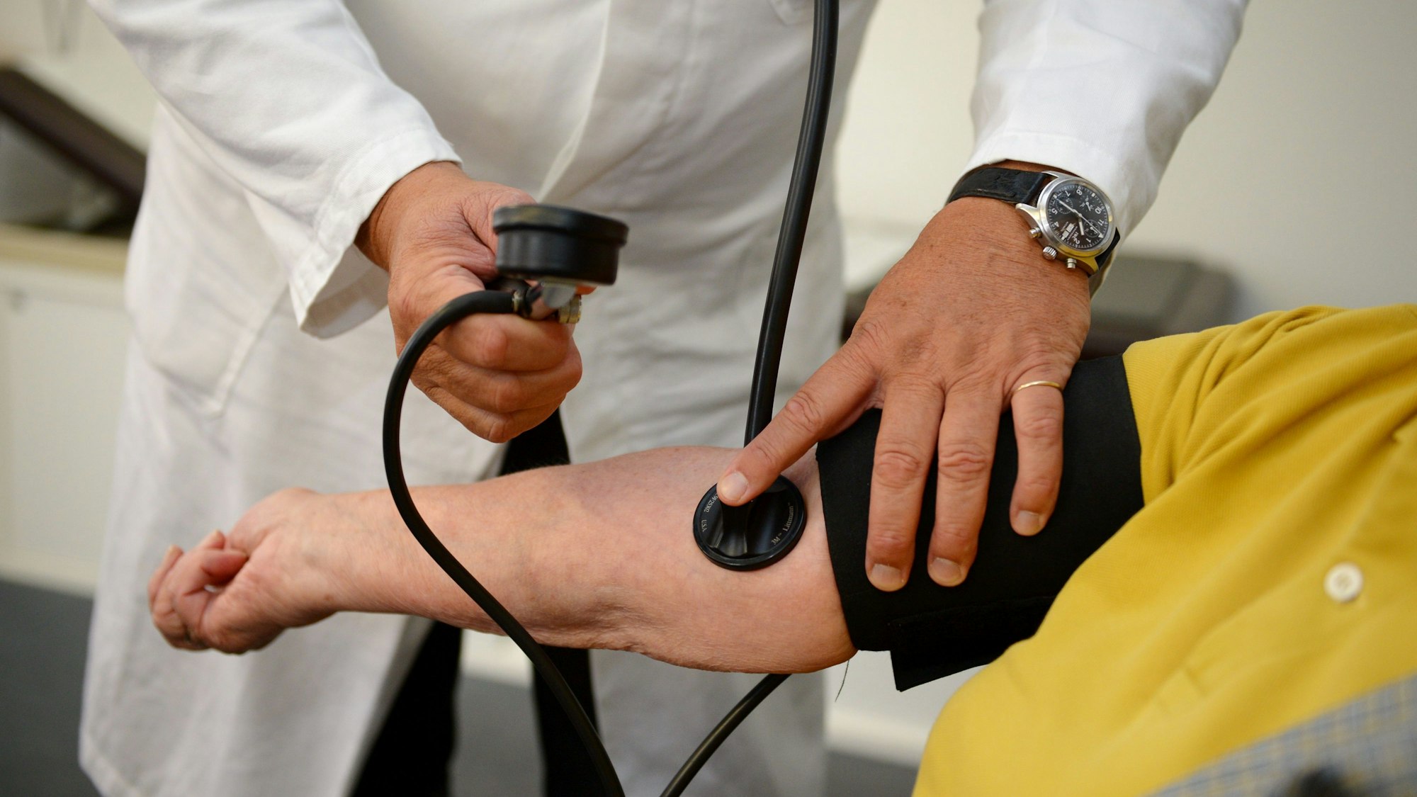 Ein Hausarzt misst in seiner Praxis einer Patientin den Blutdruck.