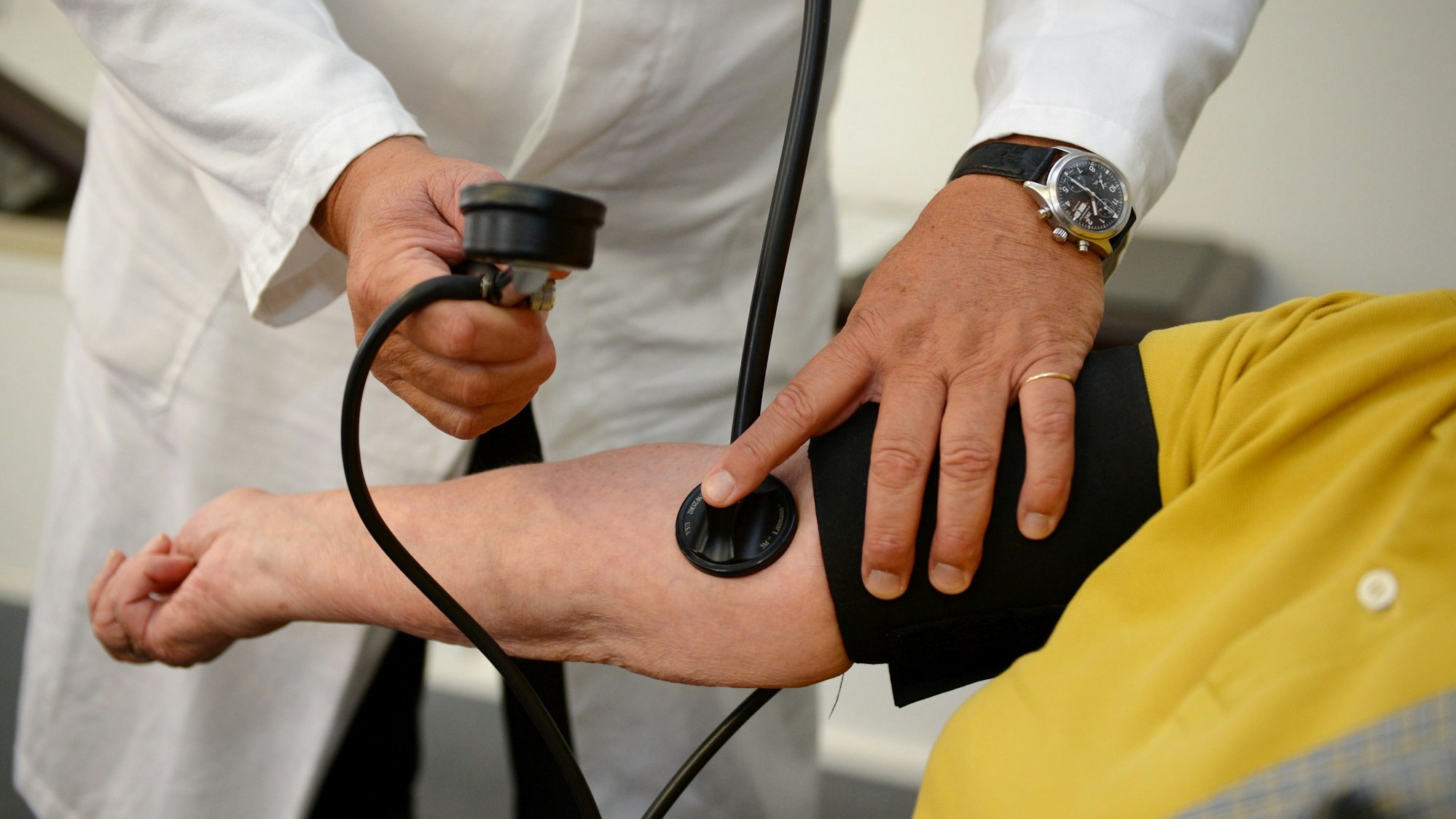 Ein Hausarzt misst in seiner Praxis einer Patientin den Blutdruck.