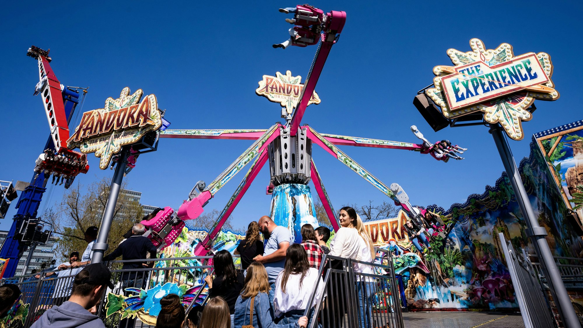 Beliebtes Vergnügen: Die Kirmes am Deutzer Rheinufer. Jugendliche warten darauf, in die Gondeln der Krake Pandorra steigen zu können. Und das alles bei leuchtend blauem Himmel.