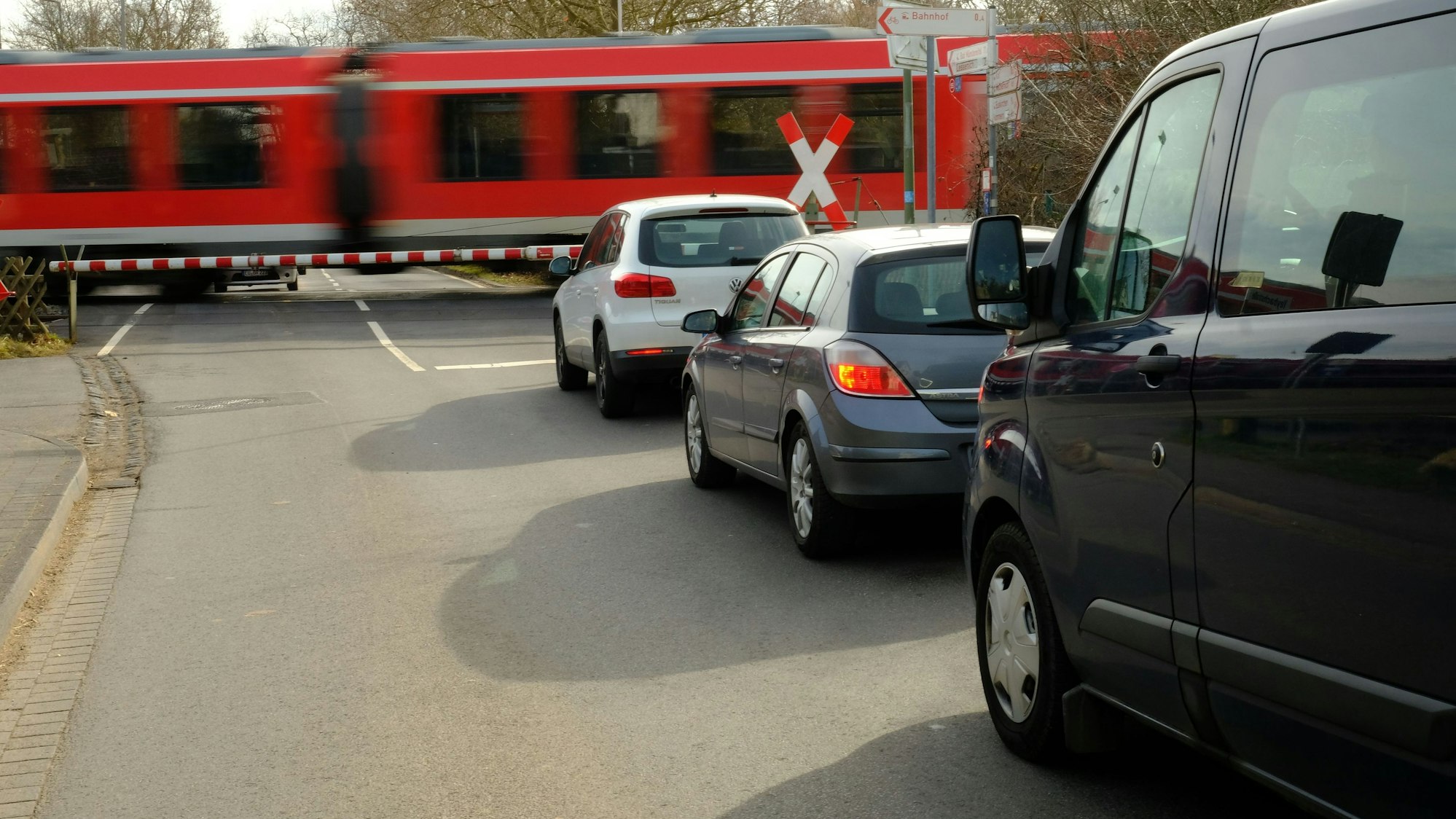 Vor dem Bahnübergang in Satzvey warten mehrere Autos, während ein Zug vorbeifährt.