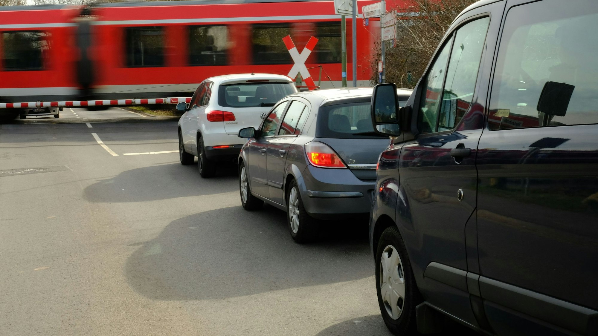 An einer geschlossenen Bahnschranke staut sich der Autoverkehr. Ein Zug fährt vorbei.