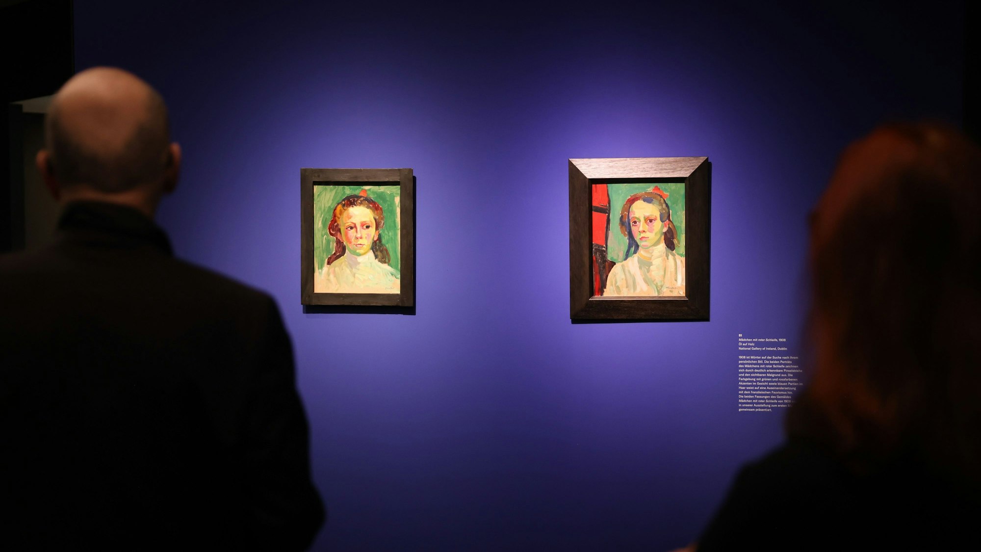 Menschen stehen bei einer Pressevorbesichtigung der Ausstellung „Gabriele Münter. Menschenbilder“ im Bucerius Kunstforum vor zwei Werken der Künstlerin, darunter „Mädchen mit roter Schleife“ (r).