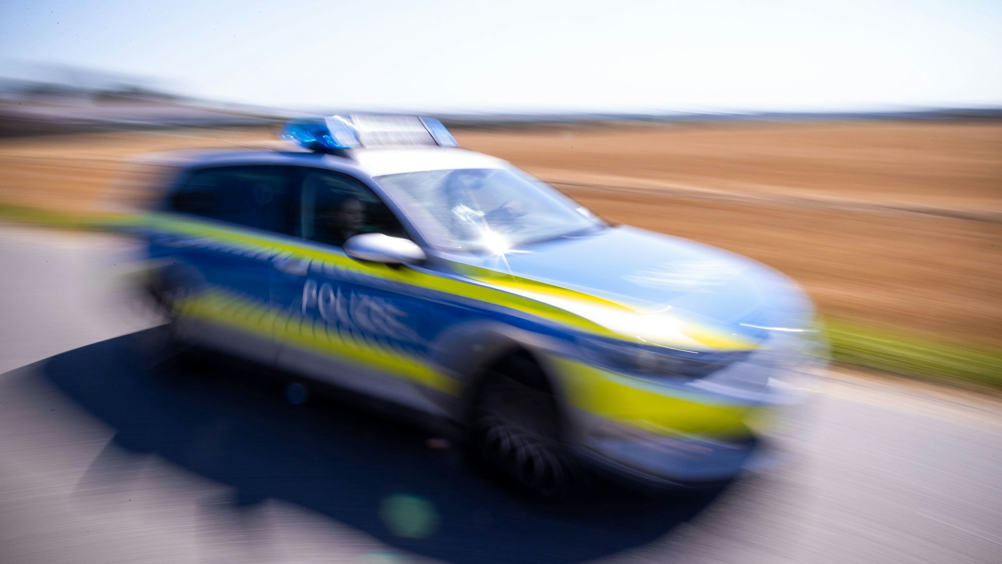 Ein Polizeiauto fährt über eine Dorfstraße. (Symbolbild)