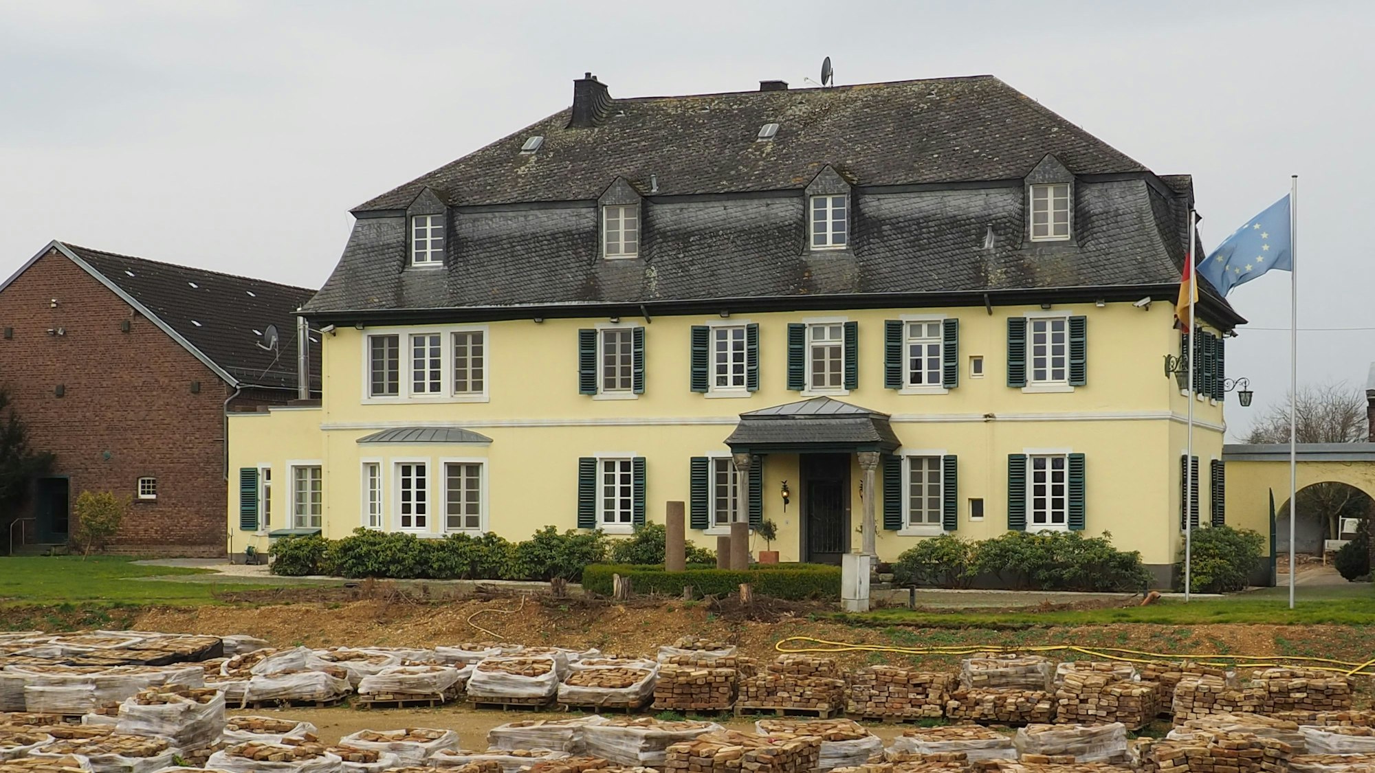 Teile des Schöddershofs sind abgerissen, die Feldbrandsteine sorgfältig gestapelt. Ein Bauzaun verdeckt den Blick auf das Gelände.