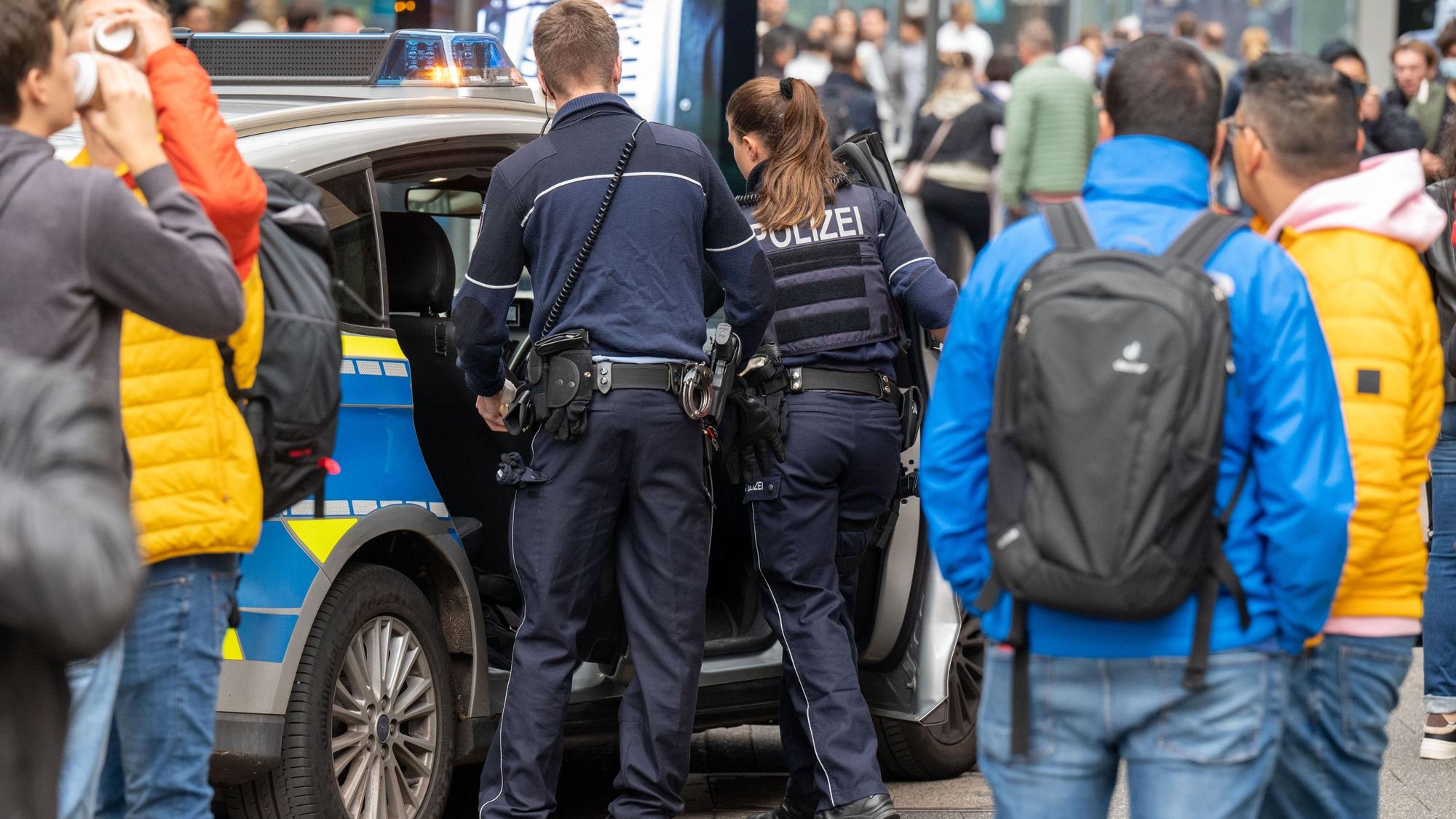 Polizeibeamte bei einem Einsatz an ihrem Streifenwagen.