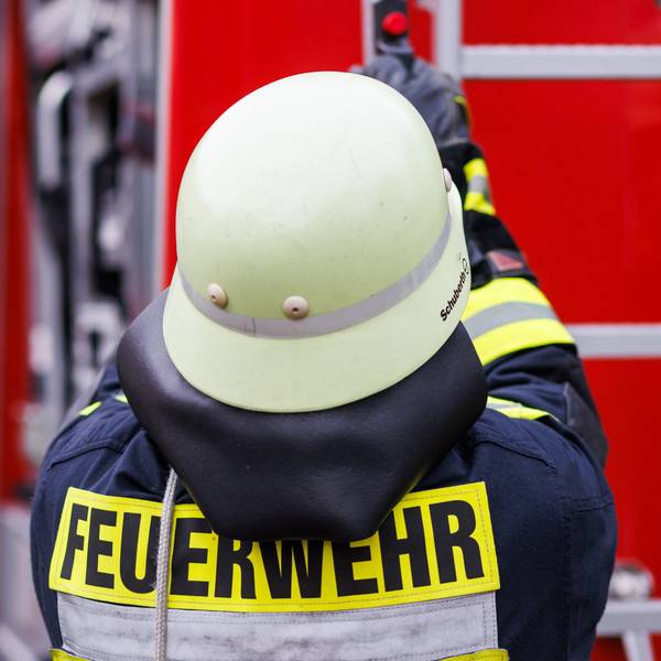 Ein Feuerwehrmann holt während einer Einsatzübung eine Leiter vom Dach eines Einsatzfahrzeugs.