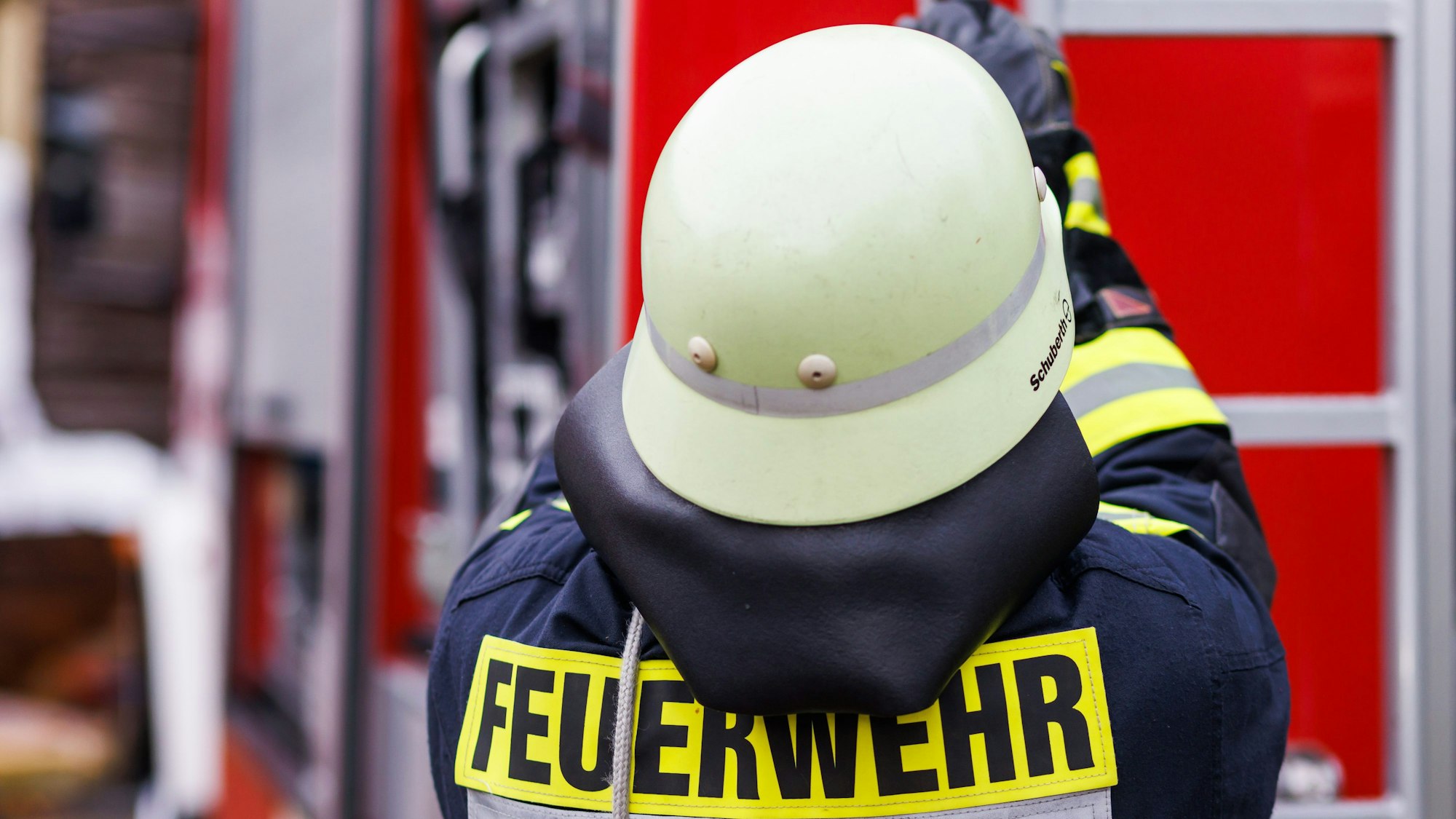 Ein Feuerwehrmann holt während einer Einsatzübung eine Leiter vom Dach eines Einsatzfahrzeugs.