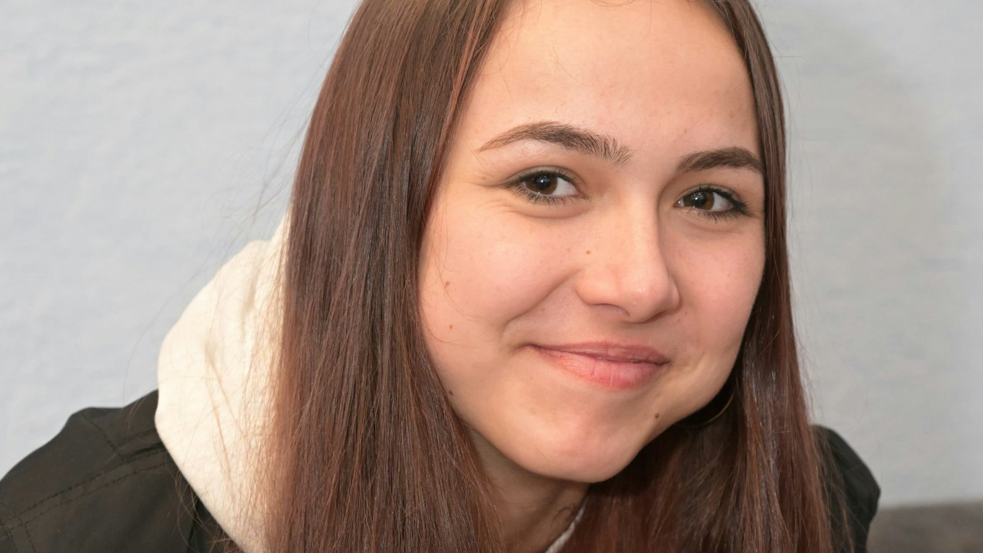 Kira Hlazacheva sitztr auf einer Couch und schaut in die Kamera.