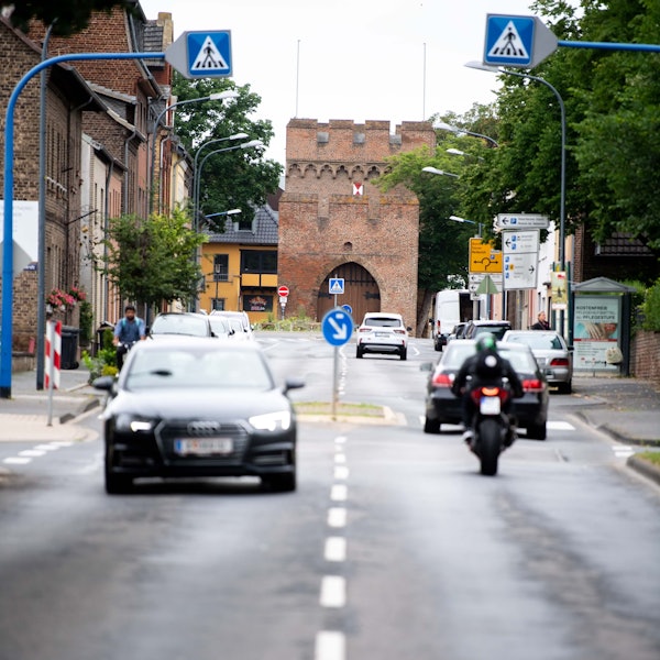Es ist die Römerallee zu sehen. Mehrere Autos fahren auf der Straße.