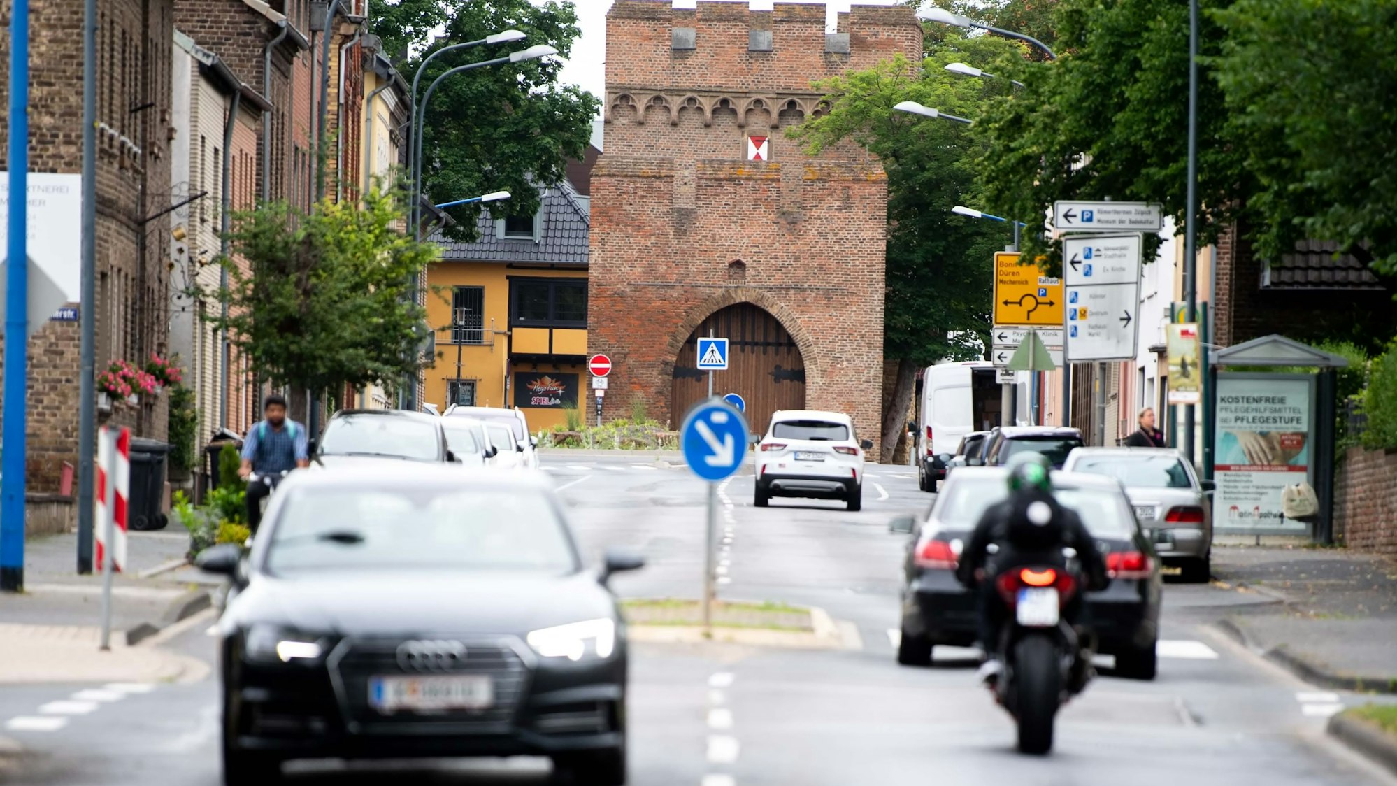 Es ist die Römerallee zu sehen. Mehrere Autos fahren auf der Straße.