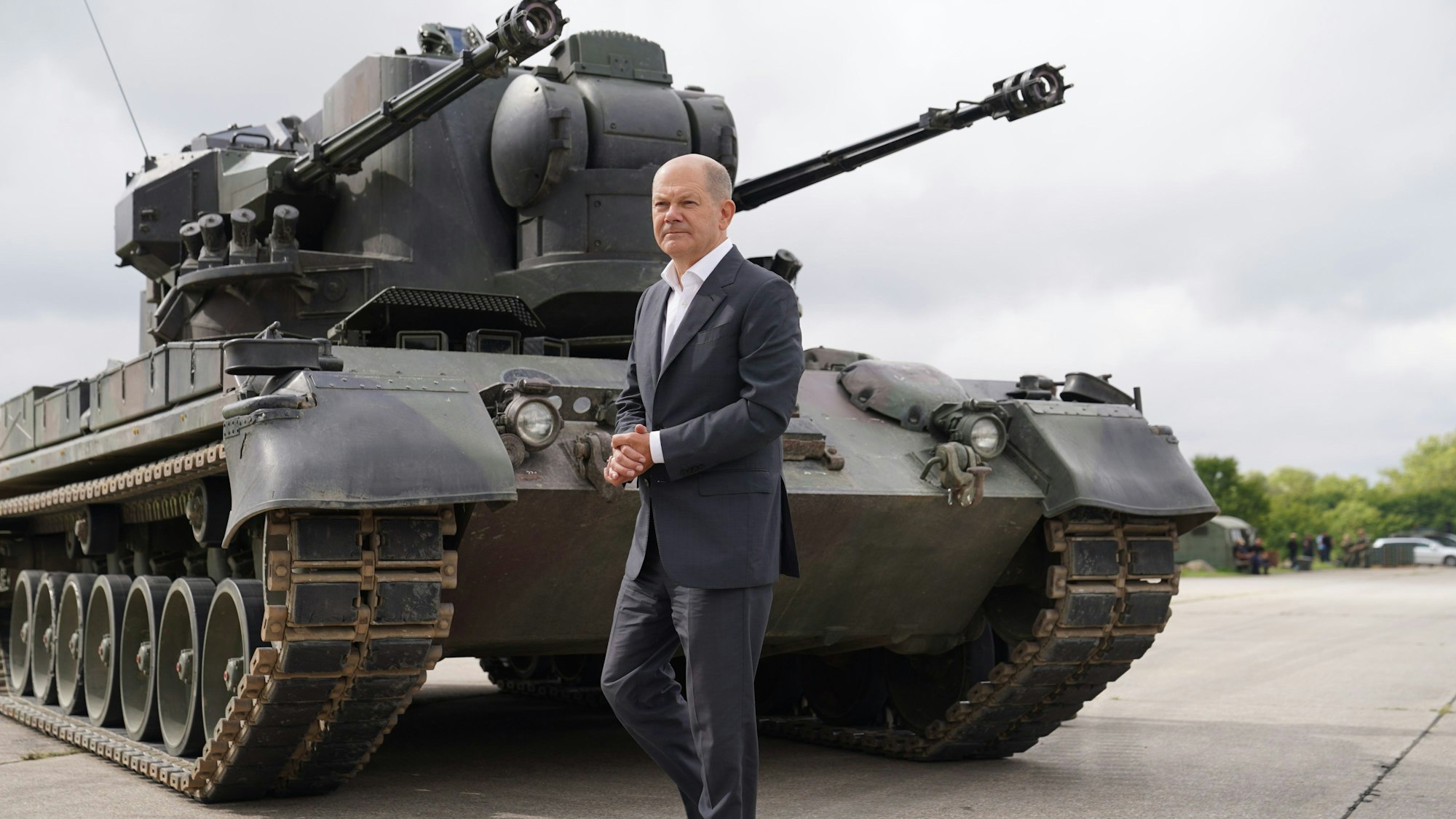 Das Foto zeigt Bundeskanzler Olaf Scholz bei einem Besuch auf dem Truppenübungsplatz das Ausbildungsprogramm für ukrainische Soldaten an dem Flugabwehrkanonenpanzer Gepard und geht an einem Gepard-Panzer vorbei.