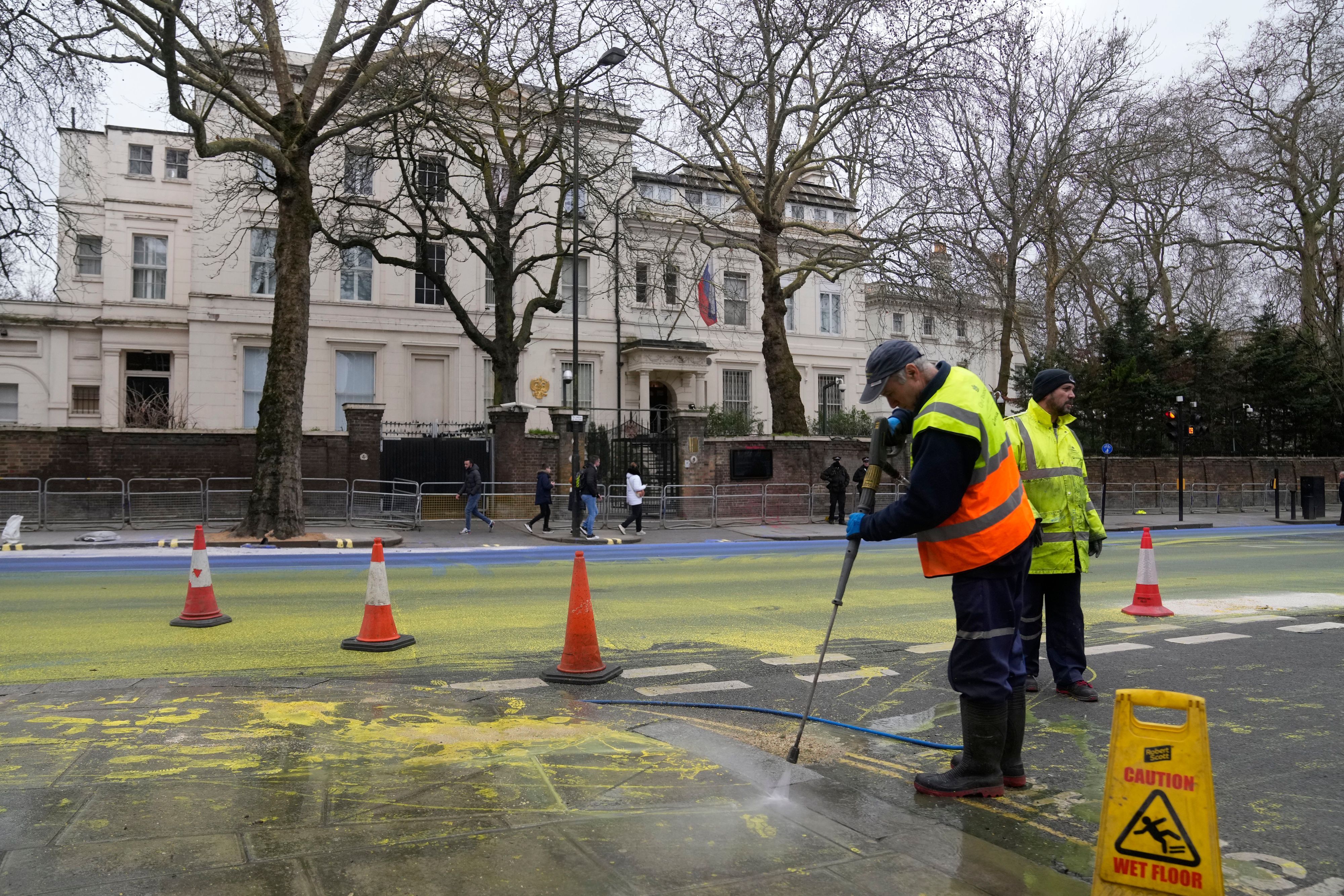 Anti-Kriegs-Aktion: Mitarbeiter der Straßenreinigung entfernen die blaue und gelbe Farbe vor der russischen Botschaft in London.