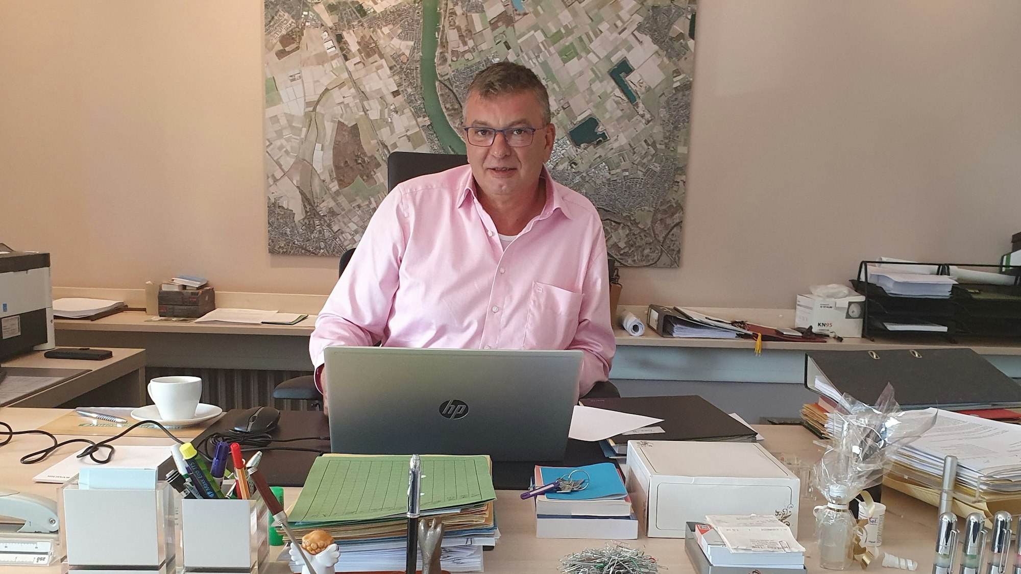 Der bisherige Bürgermeister Stephan Vehreschild sitzt am Schreibtisch in seinem Büro vor einem Stadtplan von Niederkassel.