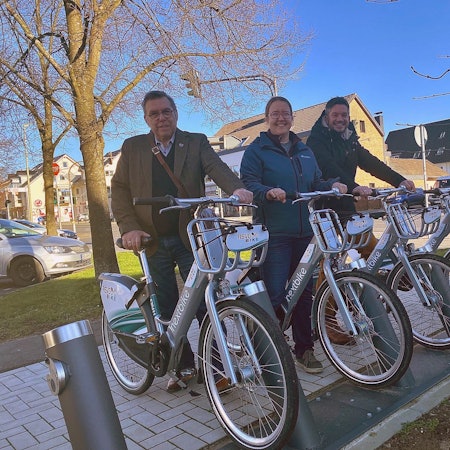 Drei Personen stehen jeweils mit einem E-Bike an der Station.