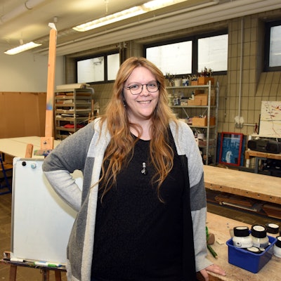 Ramona Gebel steht in einem Kunstraum, sie lächelt in die Kamera.