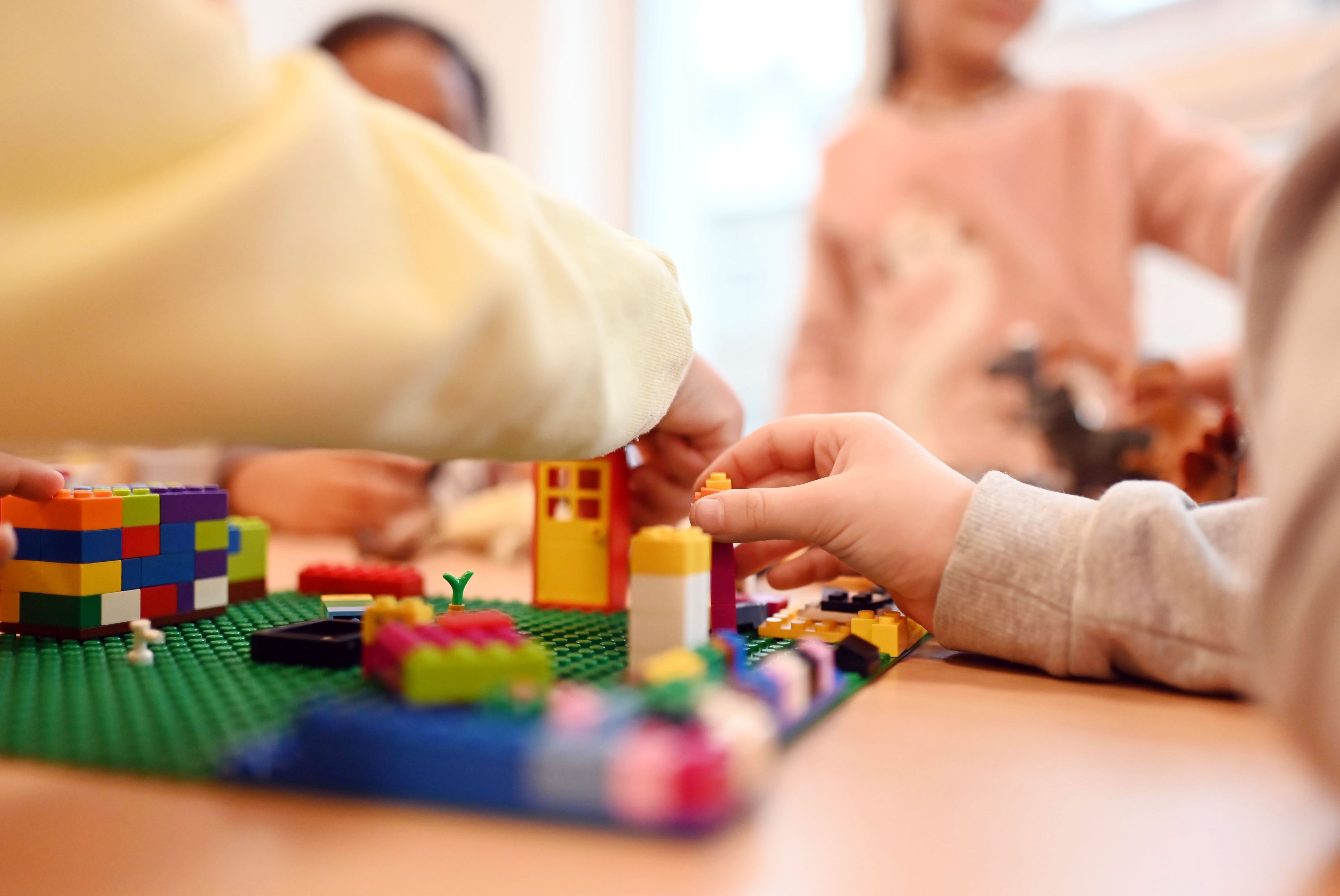 Es sind mehrere Kinderhände zu sehen, die mit Bausteinen bauen.