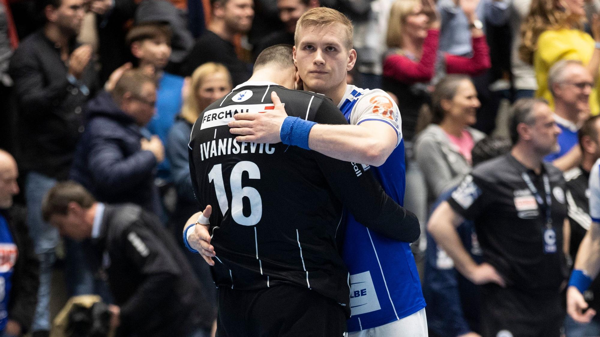 Zwei Handballspieler umarmen sich, auf ihren Gesichtern sieht man Enttäuschung.