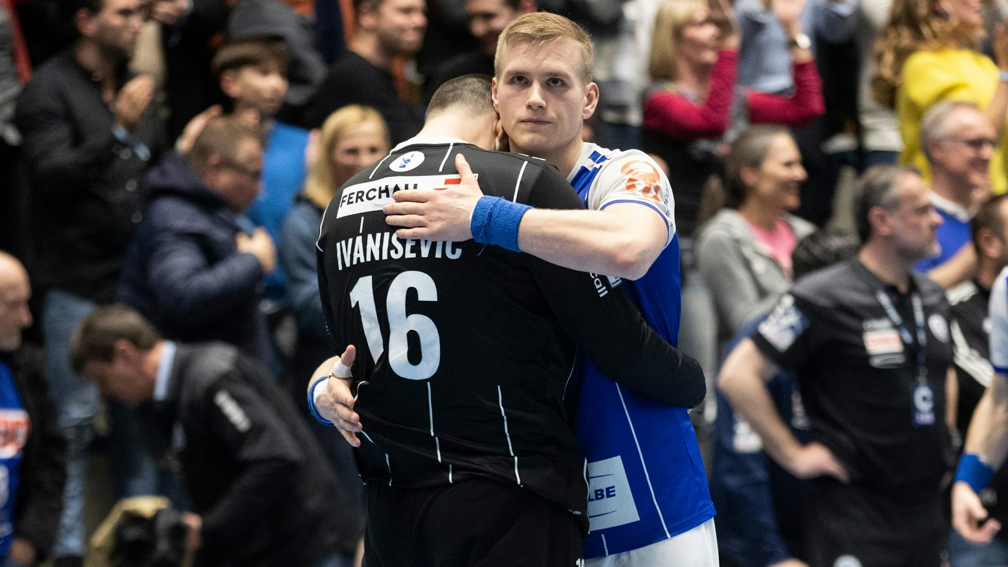 Zwei Handballspieler umarmen sich, auf ihren Gesichtern sieht man Enttäuschung.