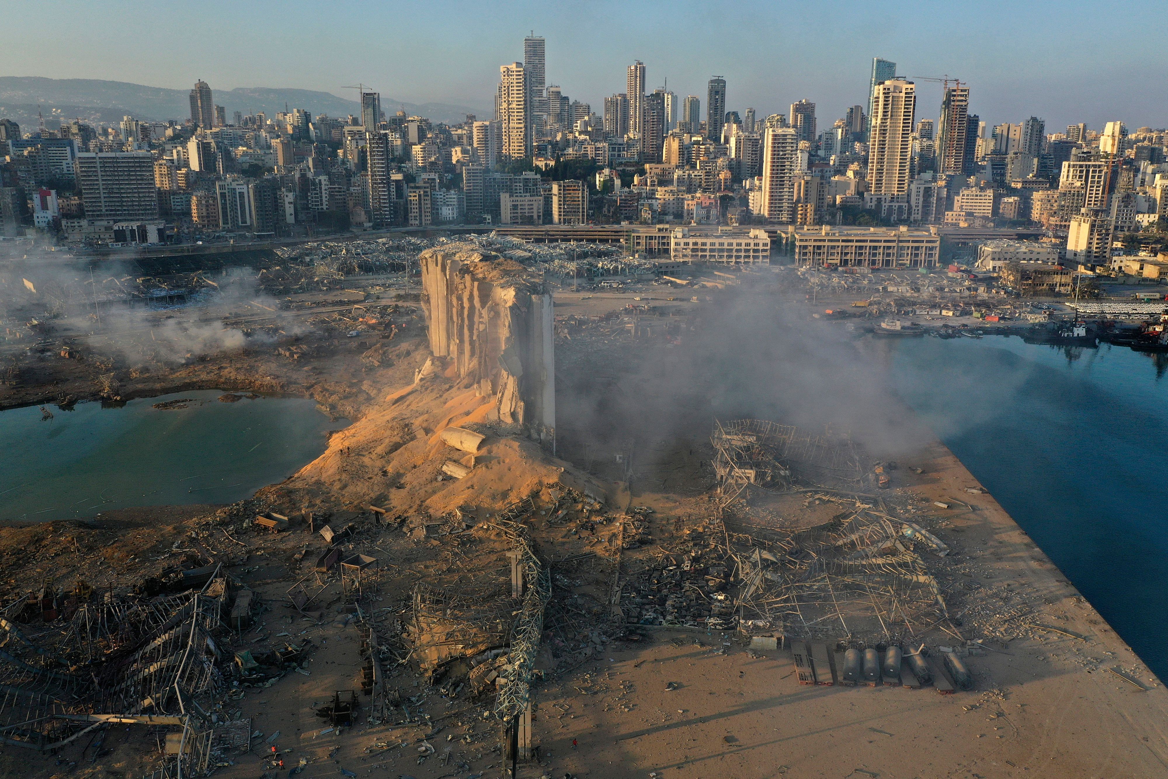 Das Bild zeigt die Zerstörung nach einer Explosion im Hafen von Beirut. Trümmer liegen herum und Rauch hängt in der Luft.