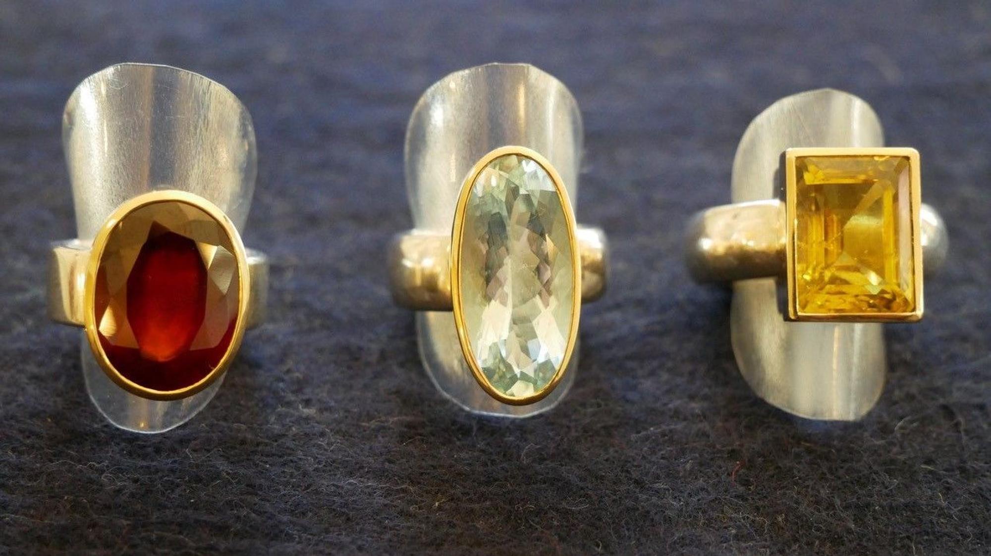 Ringe auf silbernen Metallkappen auf dunklem Stoffhintergrund