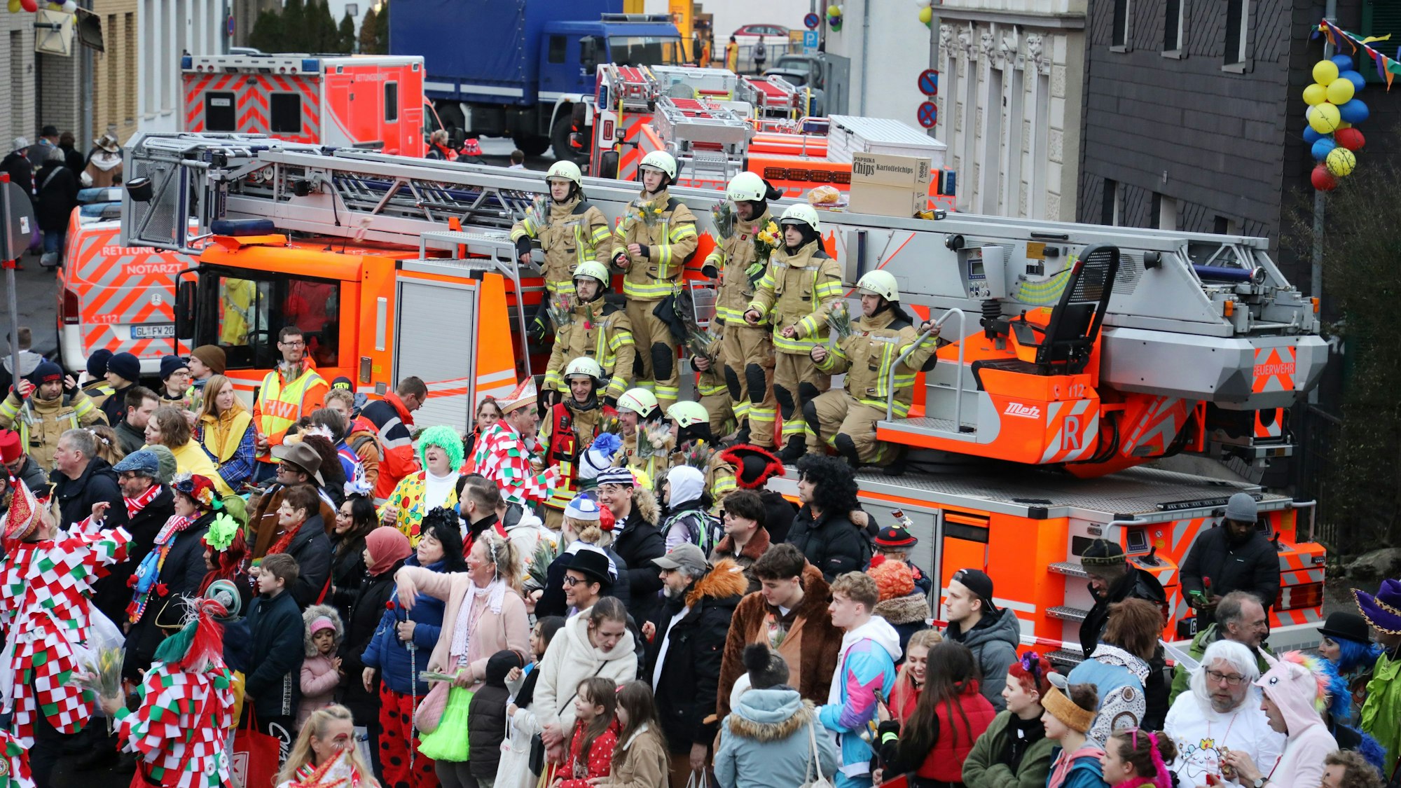 Feuerwehrleute stehen auf einem Drehleiterfahrzeug, im Hintergrund sind weitere Feuerwehrfahrzeuge, ein Rettungswagen, ein Notarzteinsatzfahrzeug und ein Lkw des Technischen Hilfswerks zu sehen.