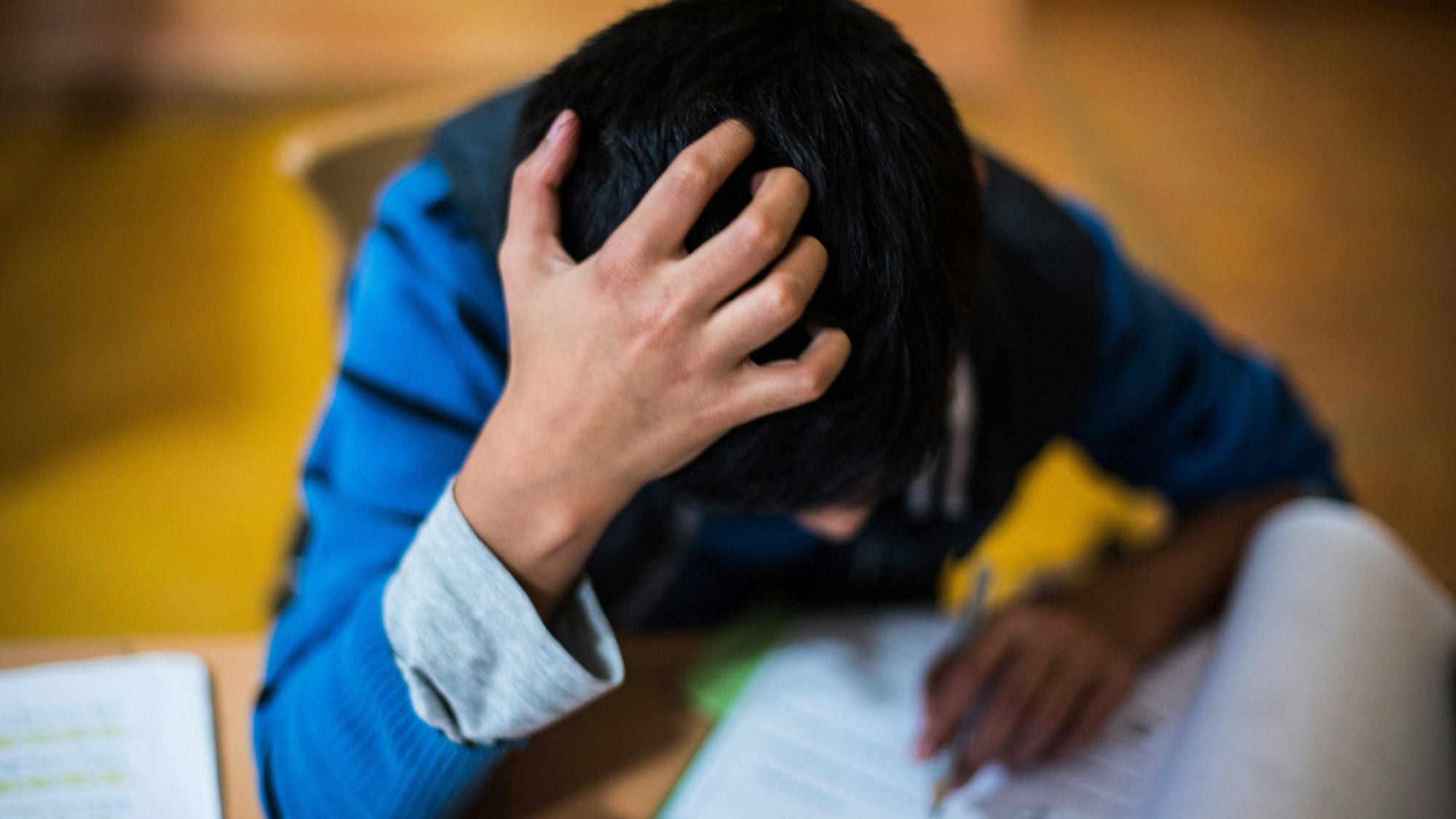 Ein Junge sitzt grübelnd in der Hausaufgabenhilfe an seinen Schularbeiten. Die Kindergrundsicherung ist im Koalitionsvertrag vereinbart worden.