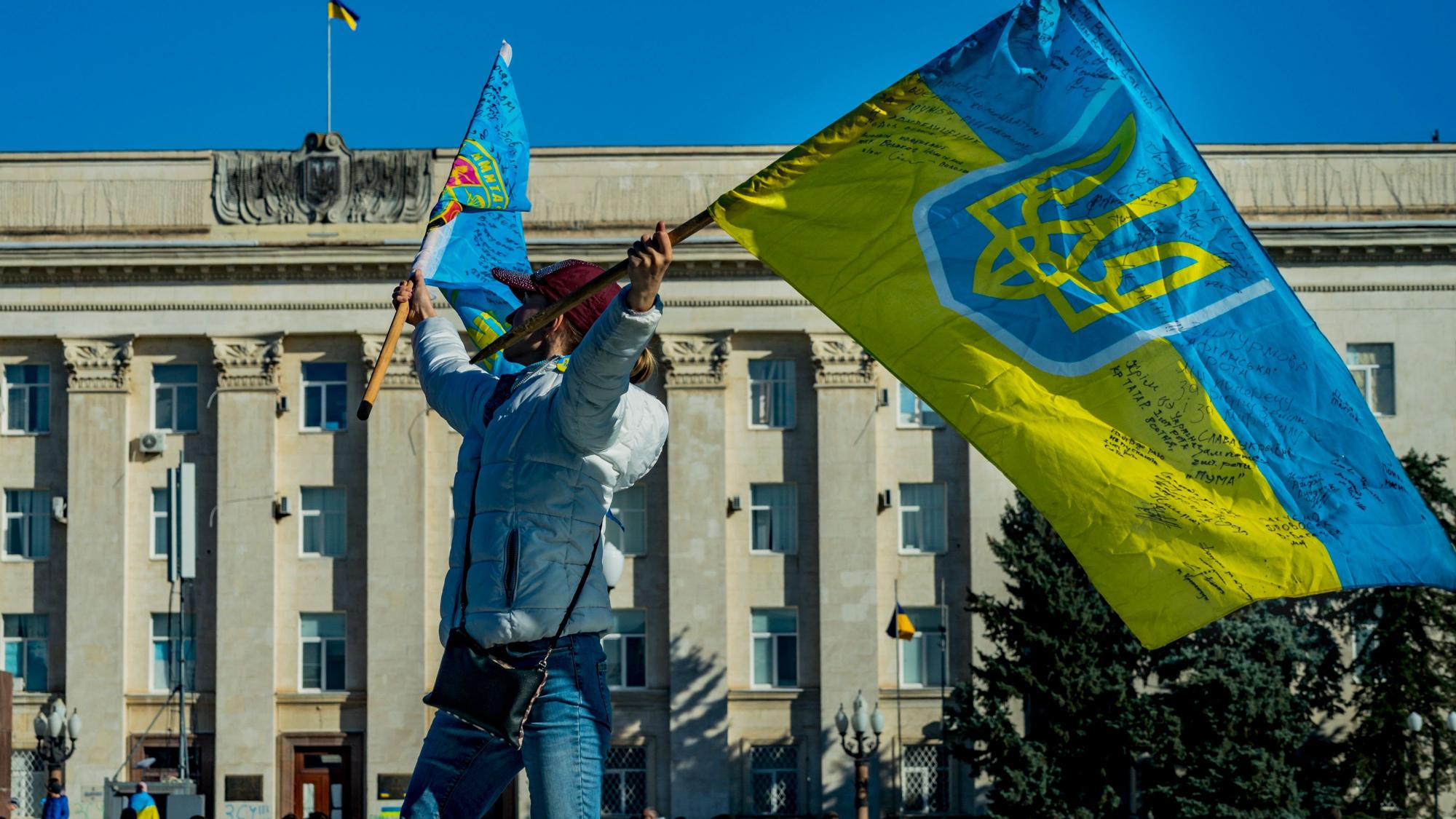 Eine Frau schwenkt eine ukrainische Flagge in der Nähe des Regierungsgebäudes von Cherson nach der Befreiung der Stadt durch die ukrainische Armee von der russischen Besatzung während des Krieges in der Ukraine. +++ dpa-Bildfunk +++