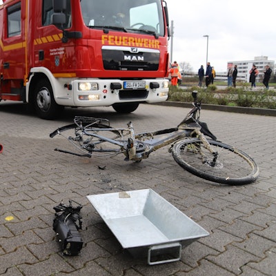 Ein kaputtes Pedelec liegt vor einem Einsatzwagen der Feuerwehr.
