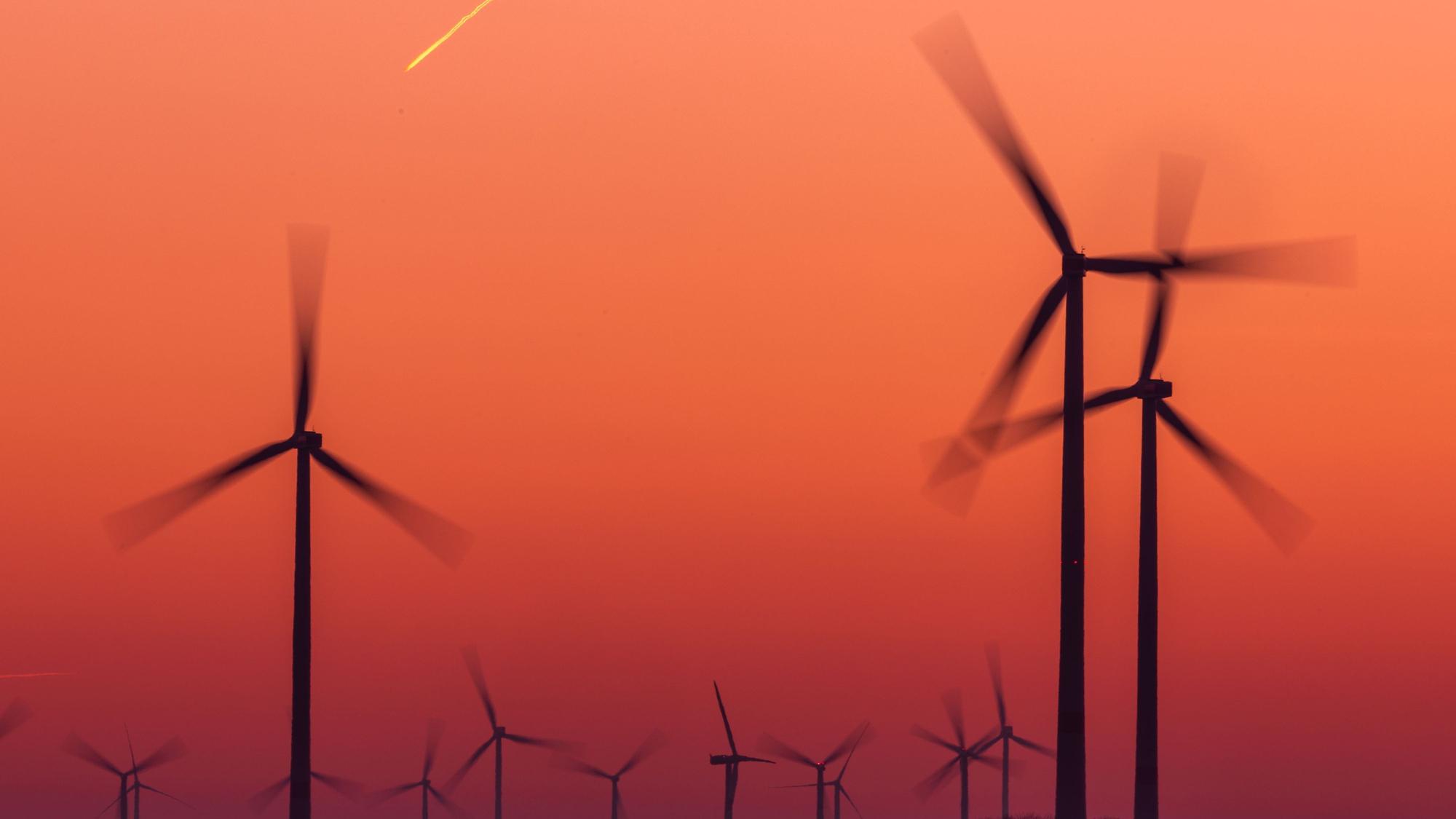 Die Rotoren von Windkraftanlagen drehen sich nach Sonnenuntergang.