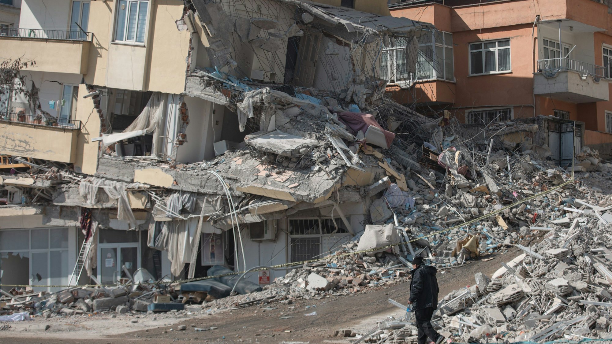 Türkei, Kharamanmaras: Ein Mann geht an einem eingestürzten Haus im Epizentrum des Erdbebens vorbei